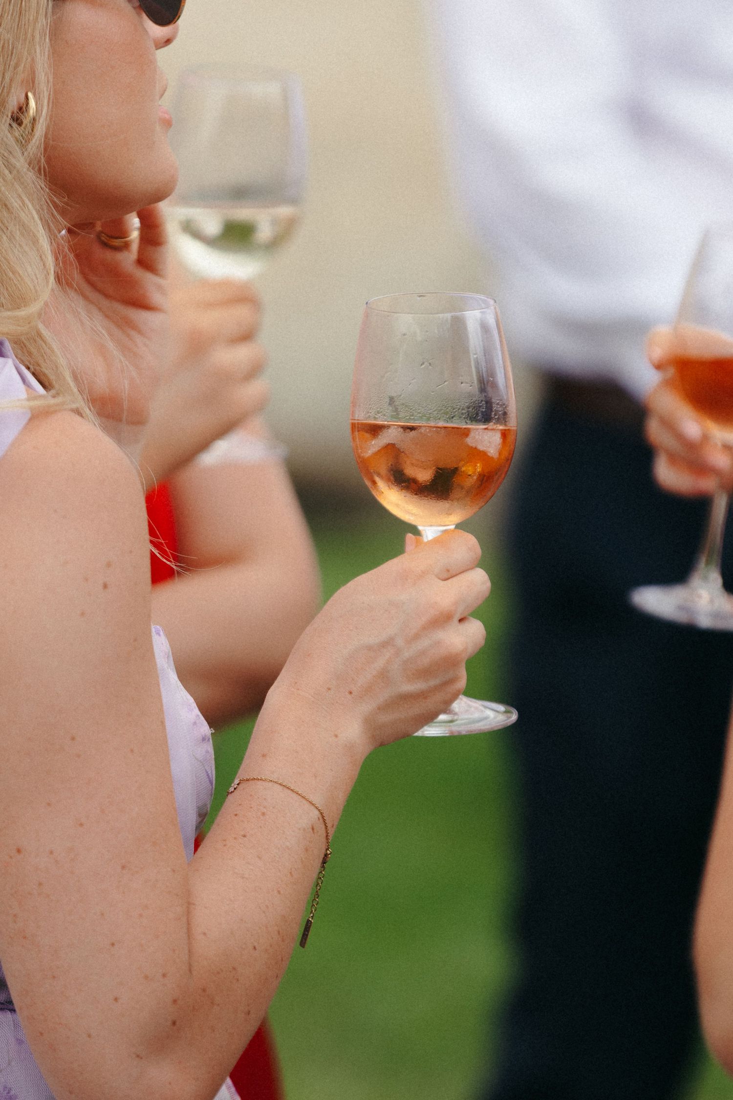 Close-up of hands holding wine glasses during outdoor celebration.