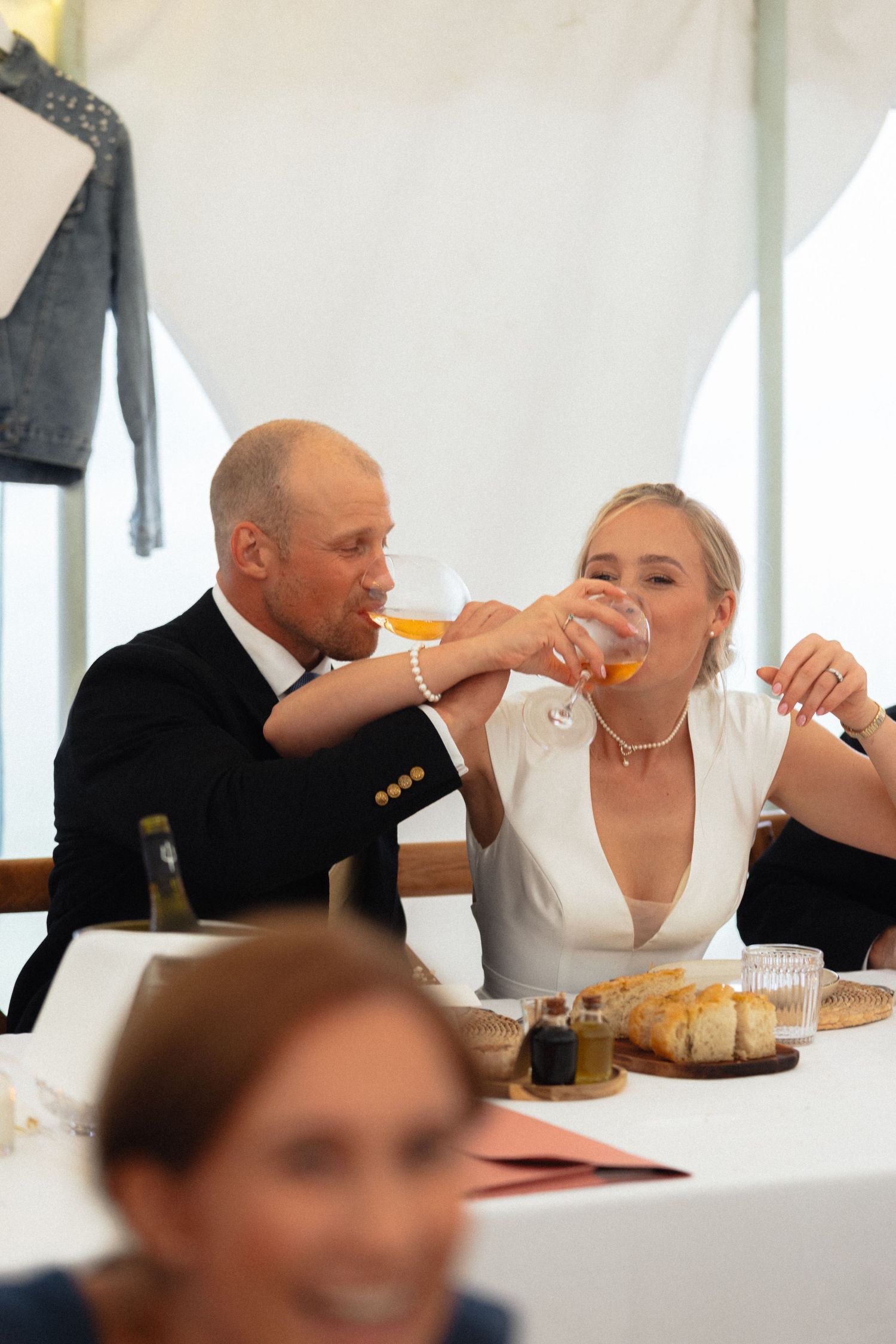 Couple shares a celebratory drink at wedding reception table.