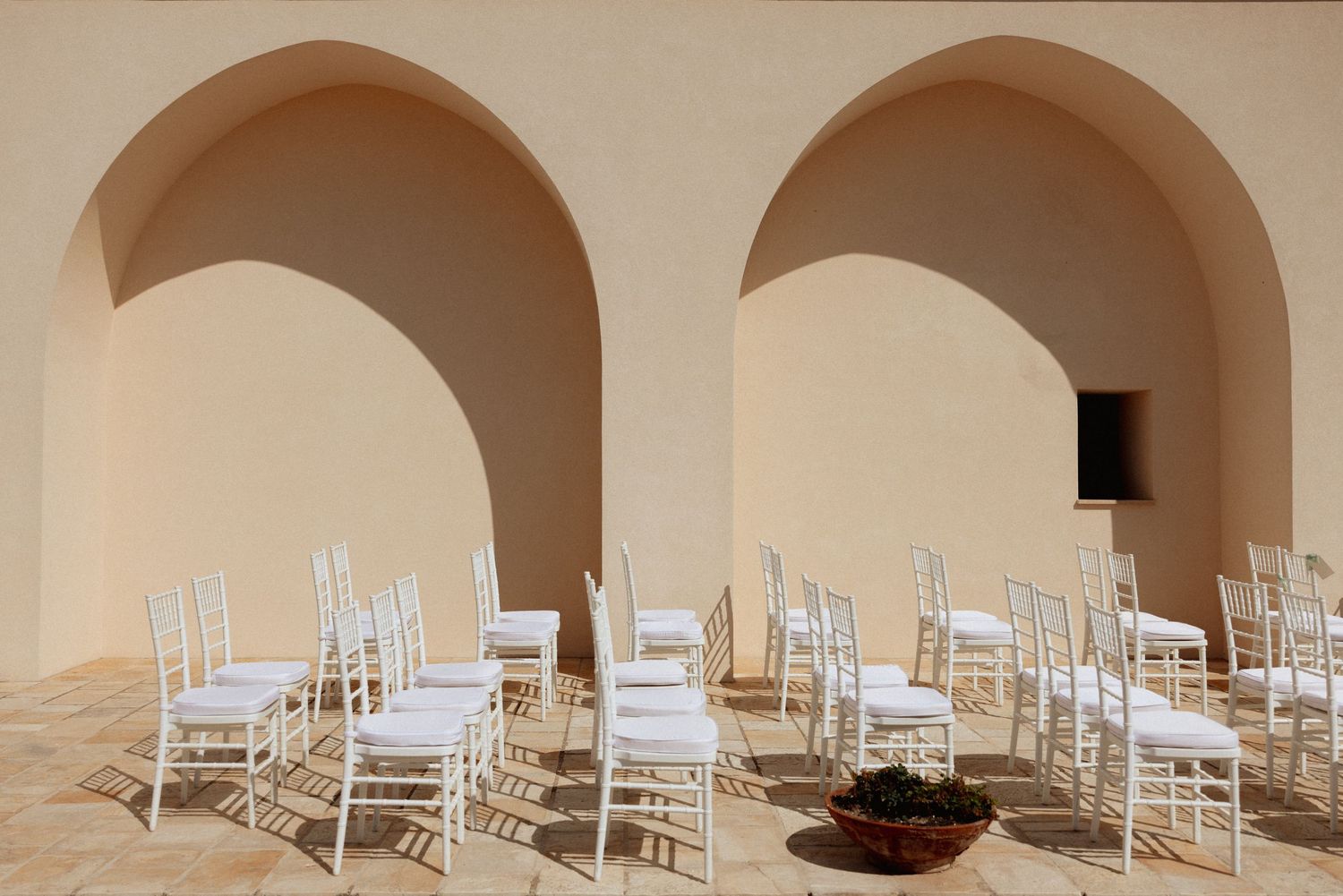 Modern event space with white chairs arranged under arched ceiling architecture.