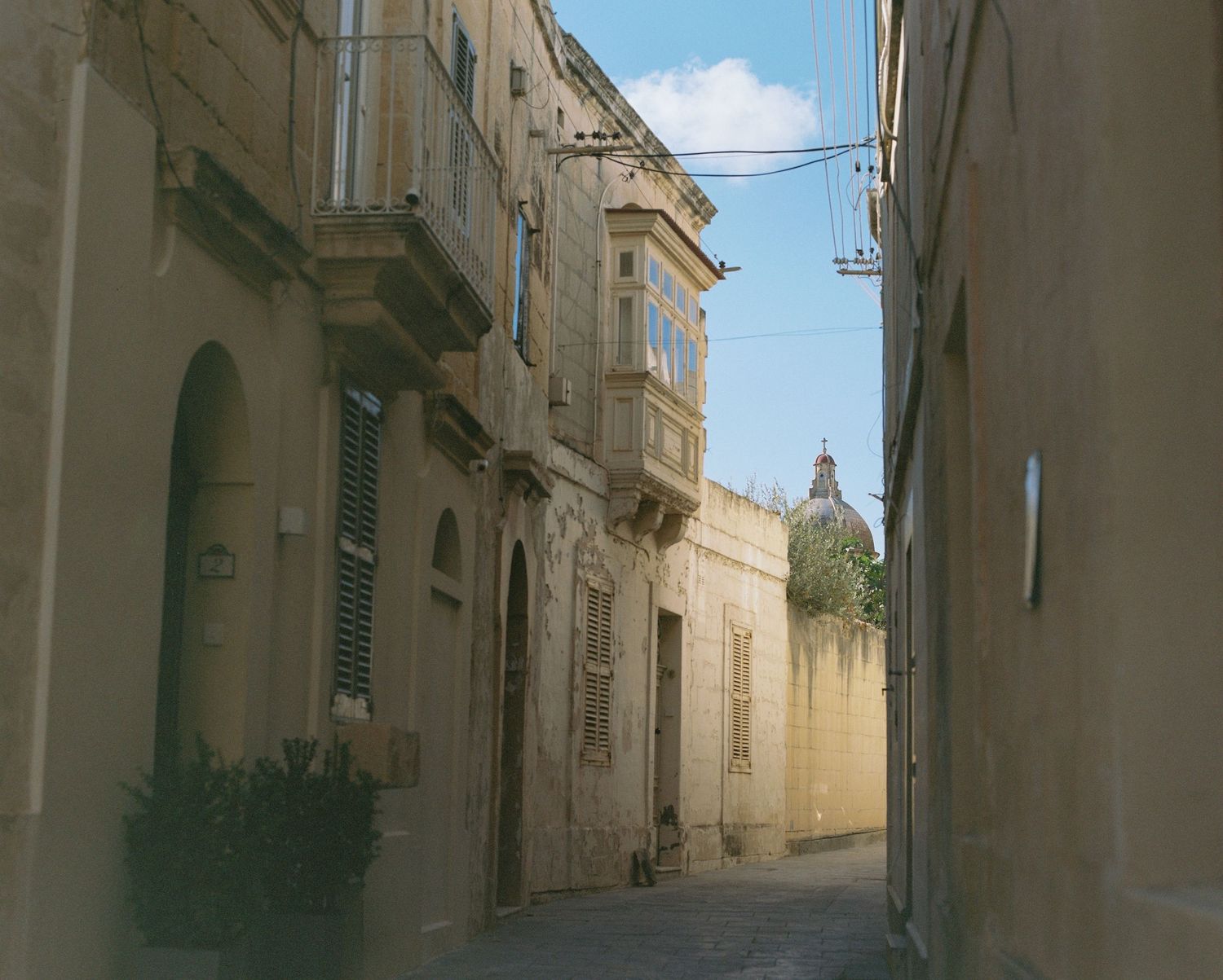 Narrow stone alleyway between traditional Mediterranean buildings.
