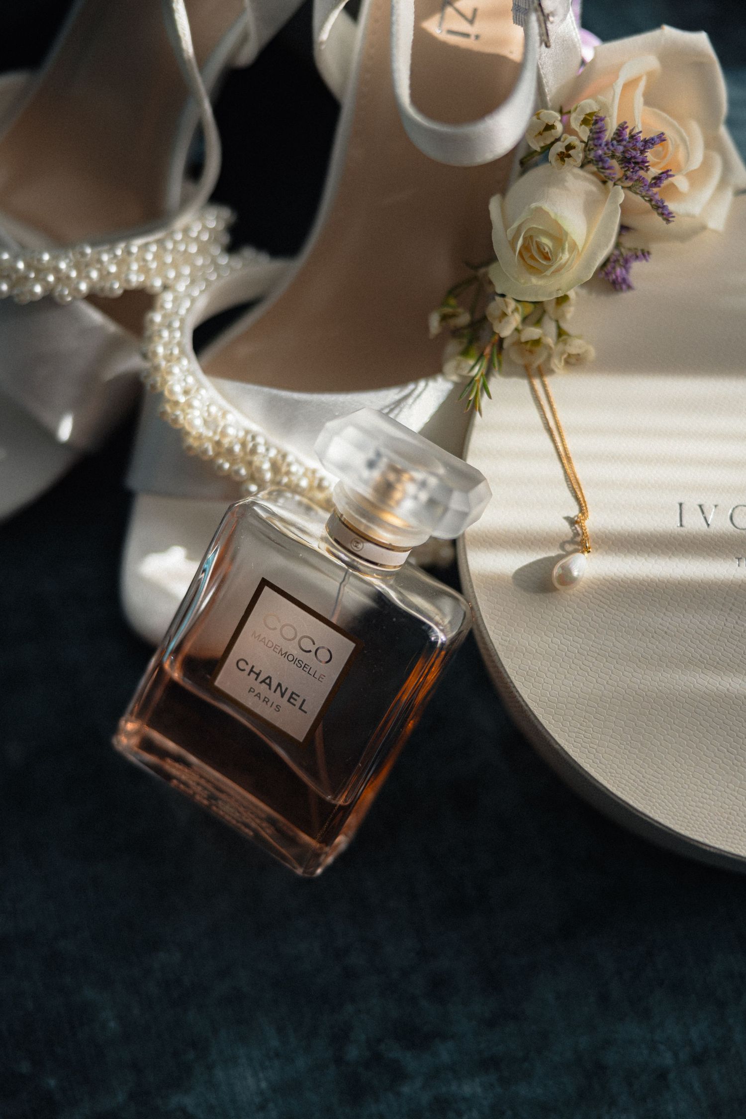 Perfume bottles and roses arranged on white surface with dramatic lighting.