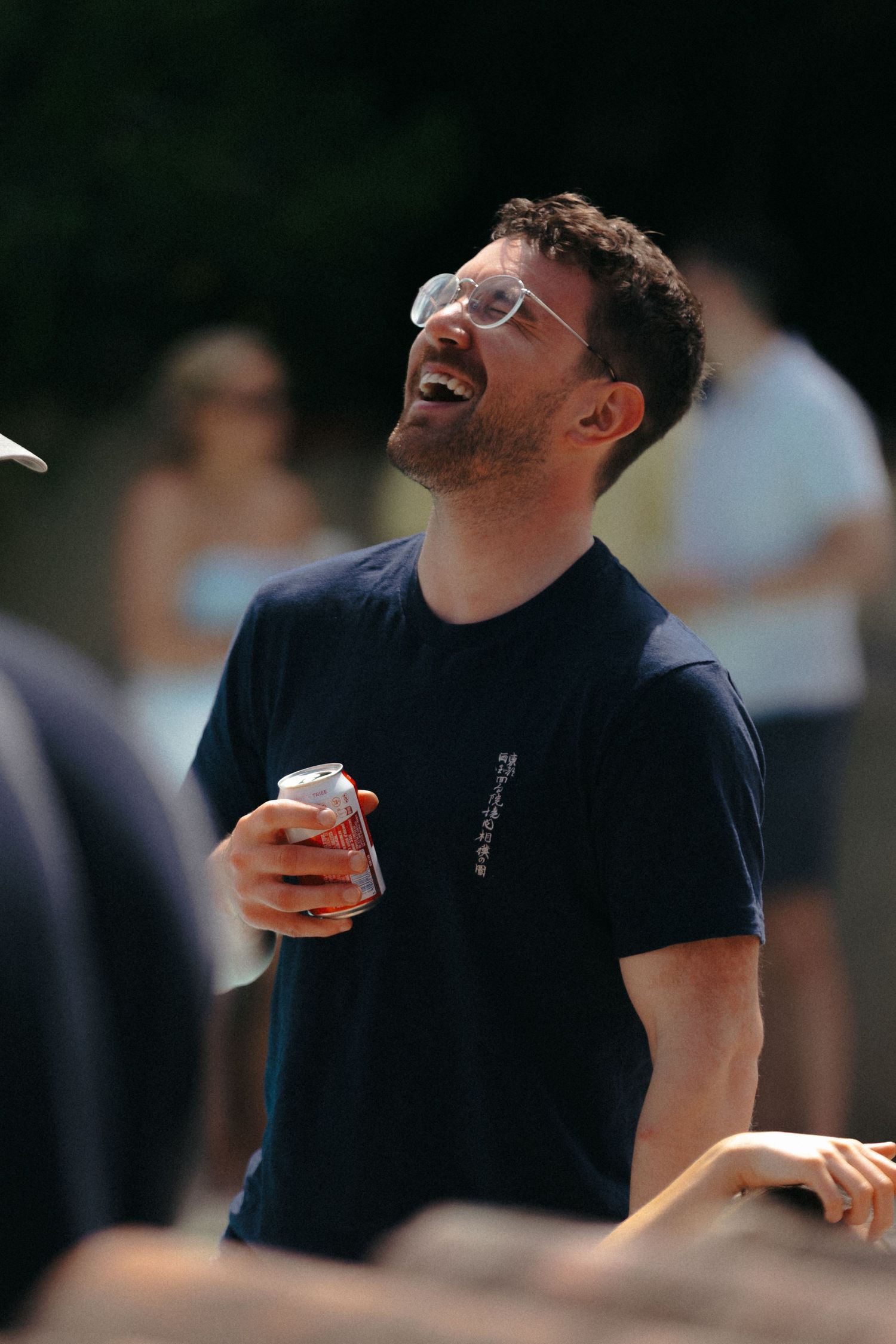 Person in a black shirt laughing joyfully outdoors.