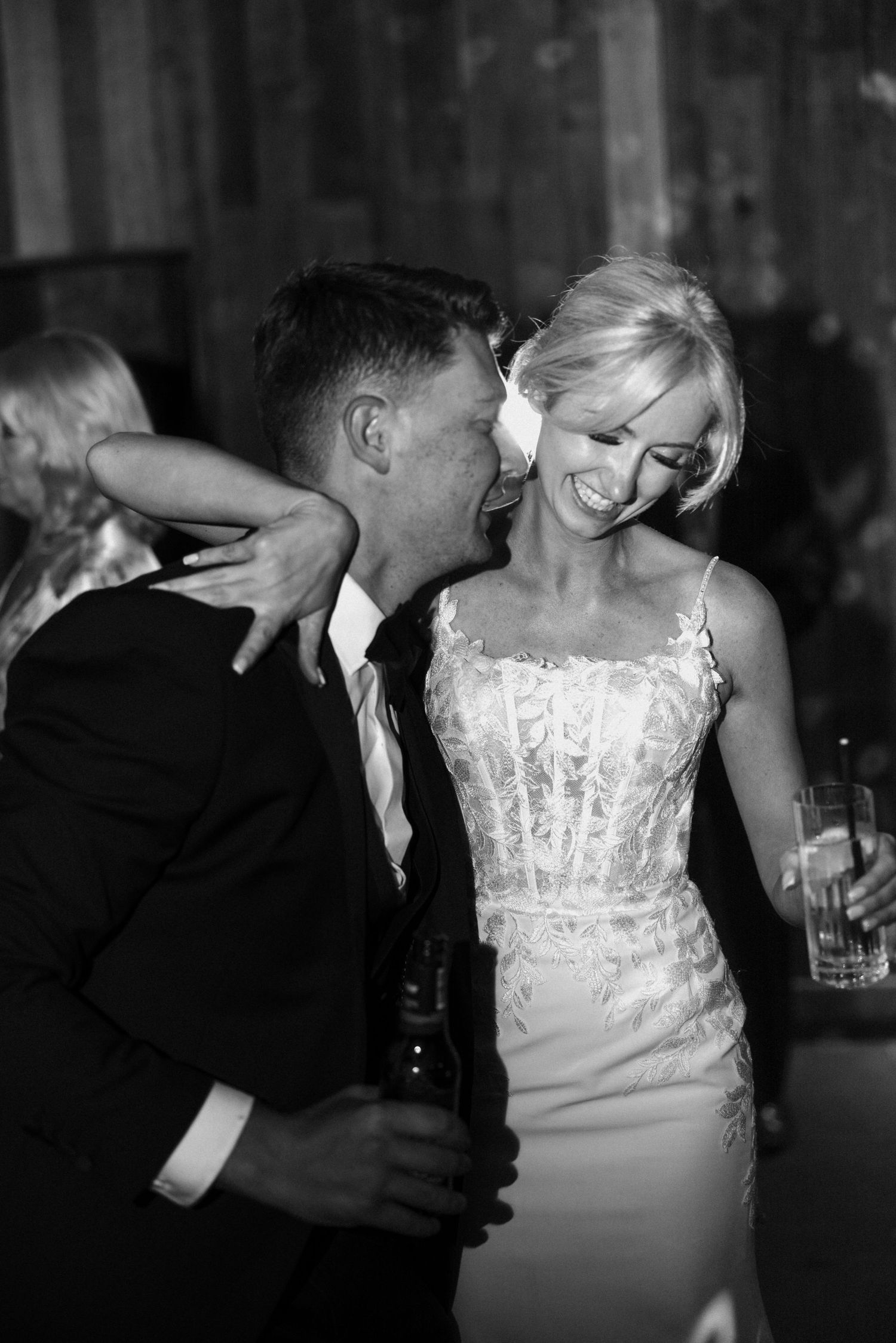 A candid black and white photo of a couple sharing a laugh during their wedding celebration.