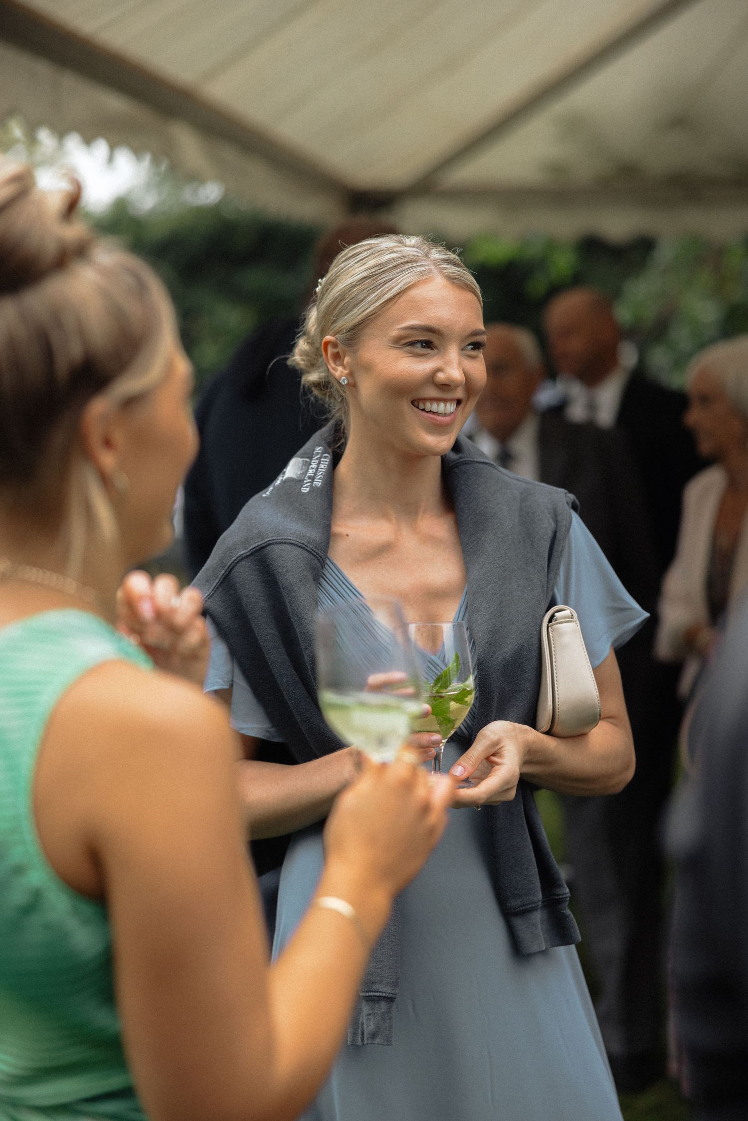 Wedding guests enjoying conversation and laughter during an outdoor reception.
