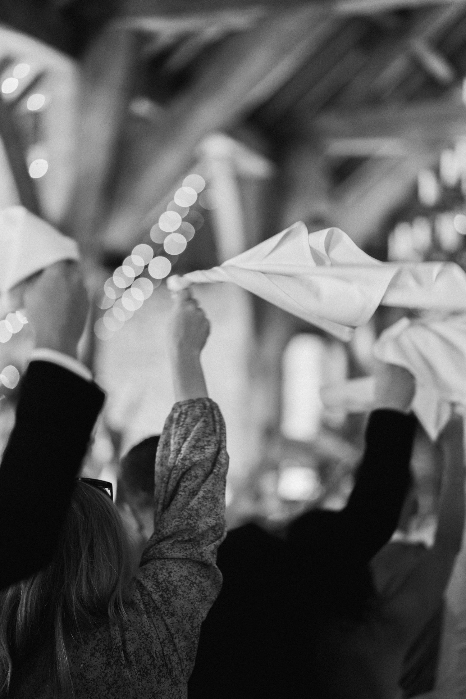 Black and white photo of guests waving napkins during a wedding celebration.