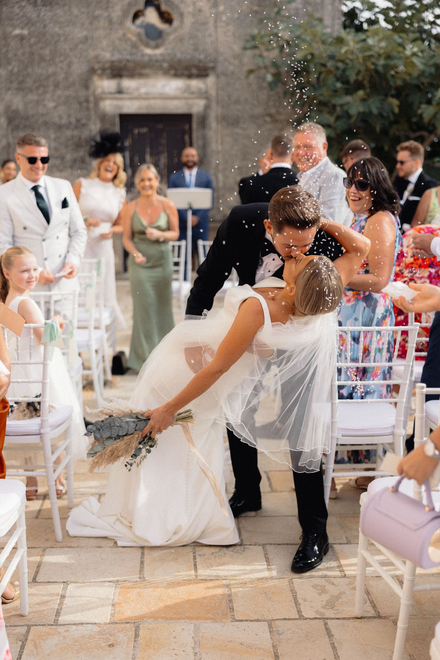Joyful wedding party celebration with confetti throws outdoors.