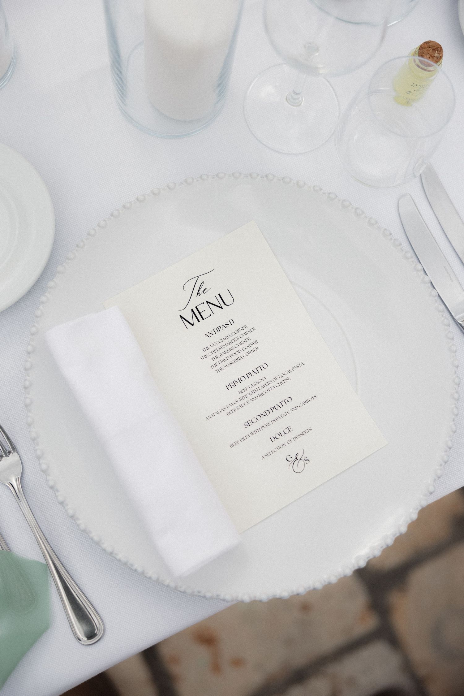 Elegant white place setting with menu card at formal wedding reception.