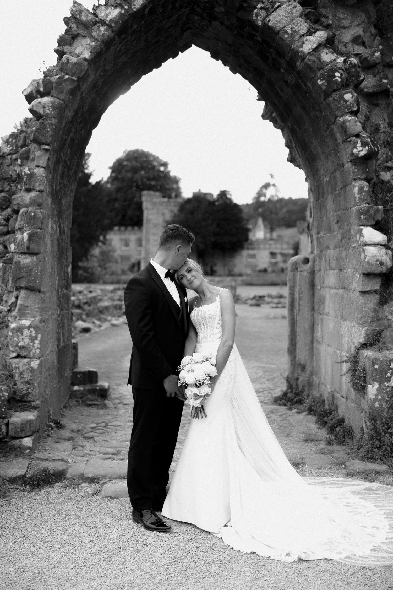 Intimate black and white wedding portrait under a stone archway.