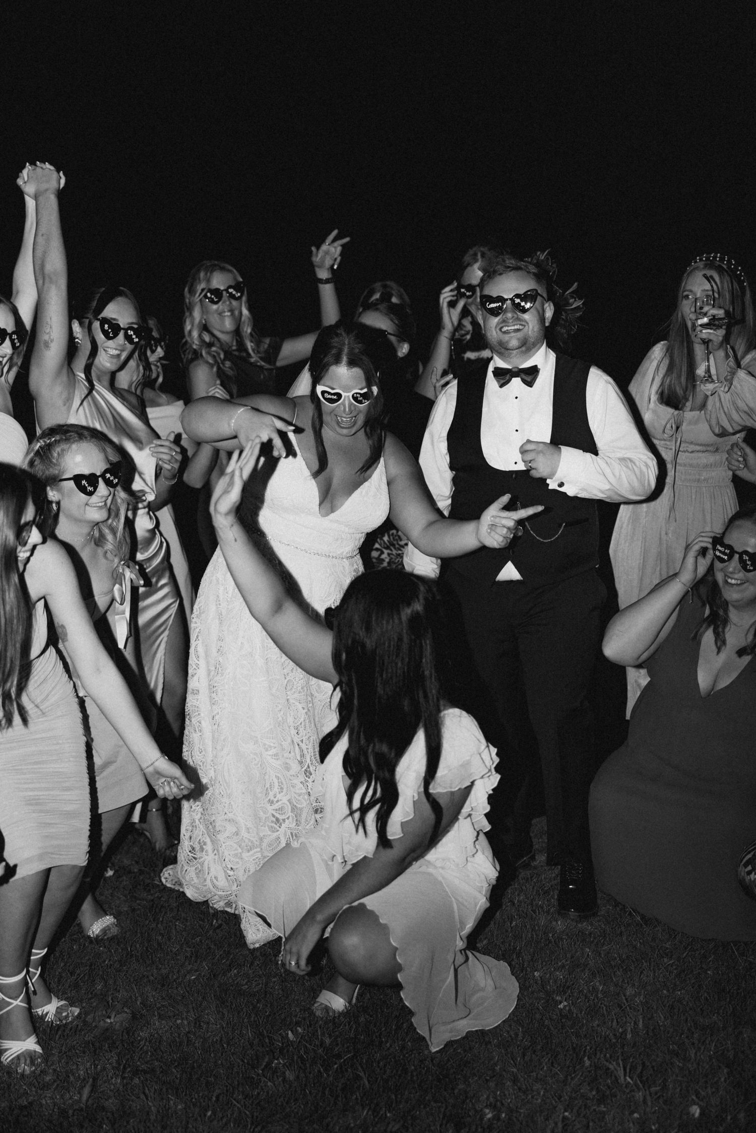 Wedding party wearing sunglasses and dancing at night outdoors.