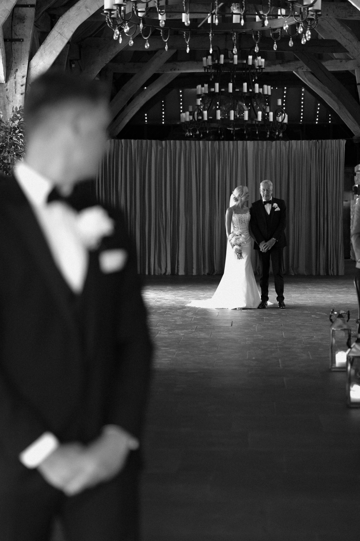 Black and white photo of wedding ceremony in rustic venue with dramatic lighting.