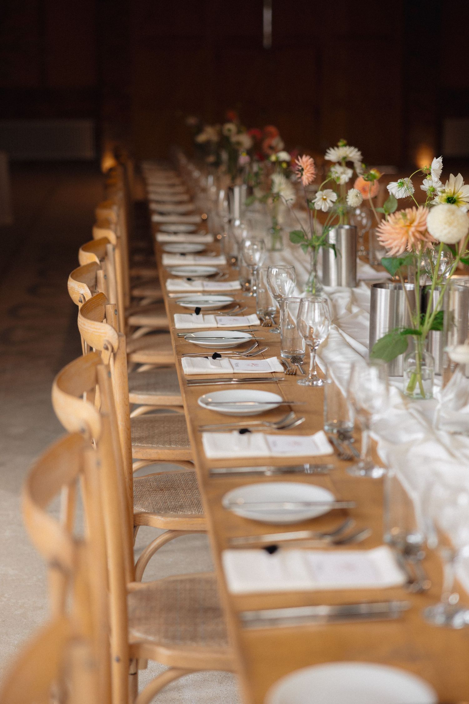 Long rustic wooden dining table set with elegant place settings and soft lighting.
