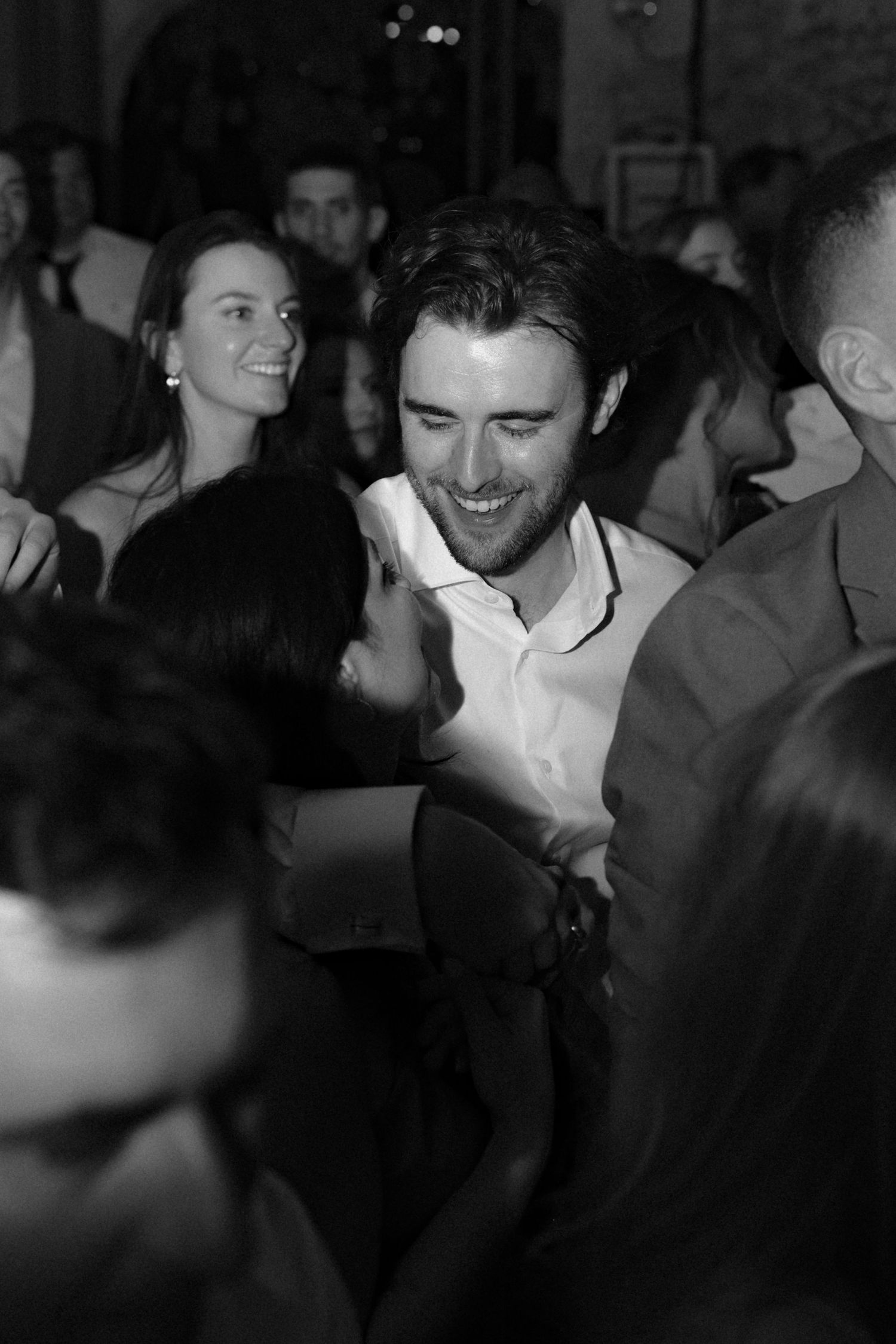 Black and white candid shot of guests enjoying themselves at an evening celebration.