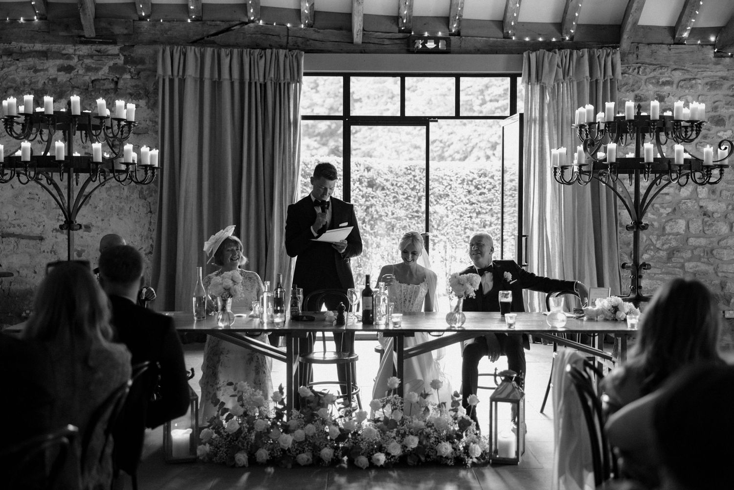 Black and white reception scene with chandeliers and large windows creating dramatic ambiance.
