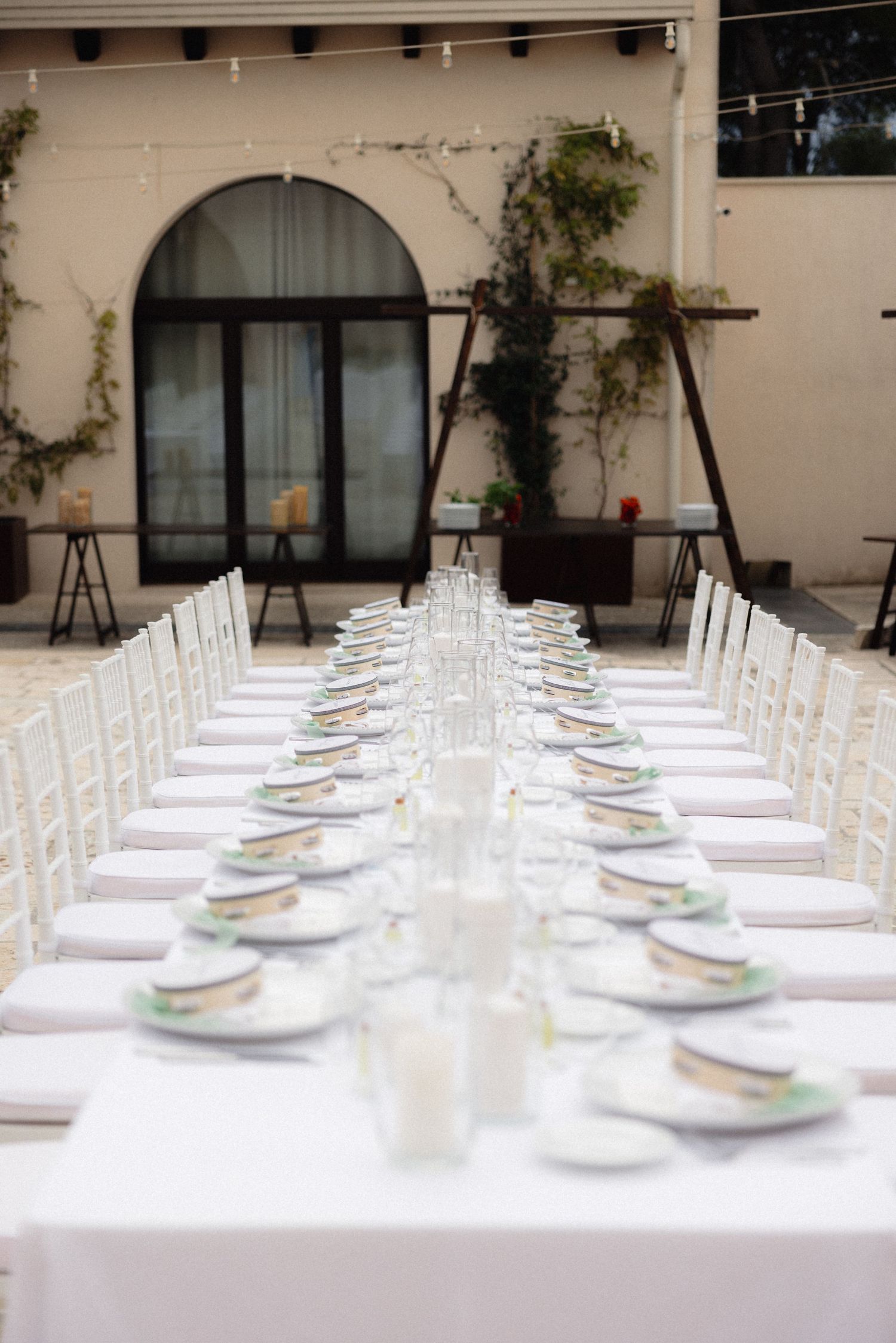 Long white dining table set for an elegant outdoor wedding reception.