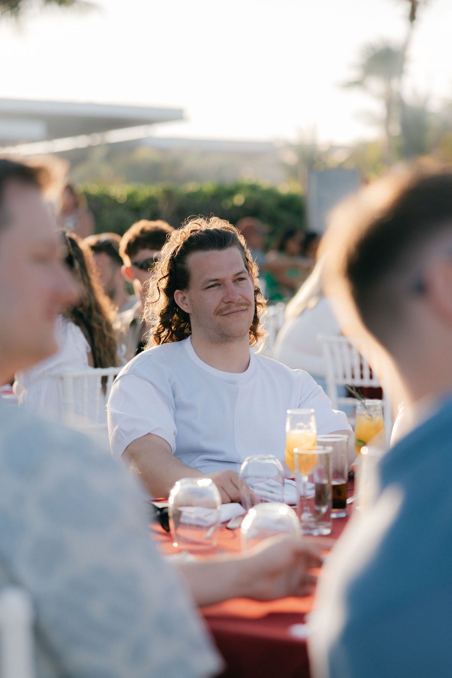 Guest enjoying drinks and conversation at outdoor sunset gathering.