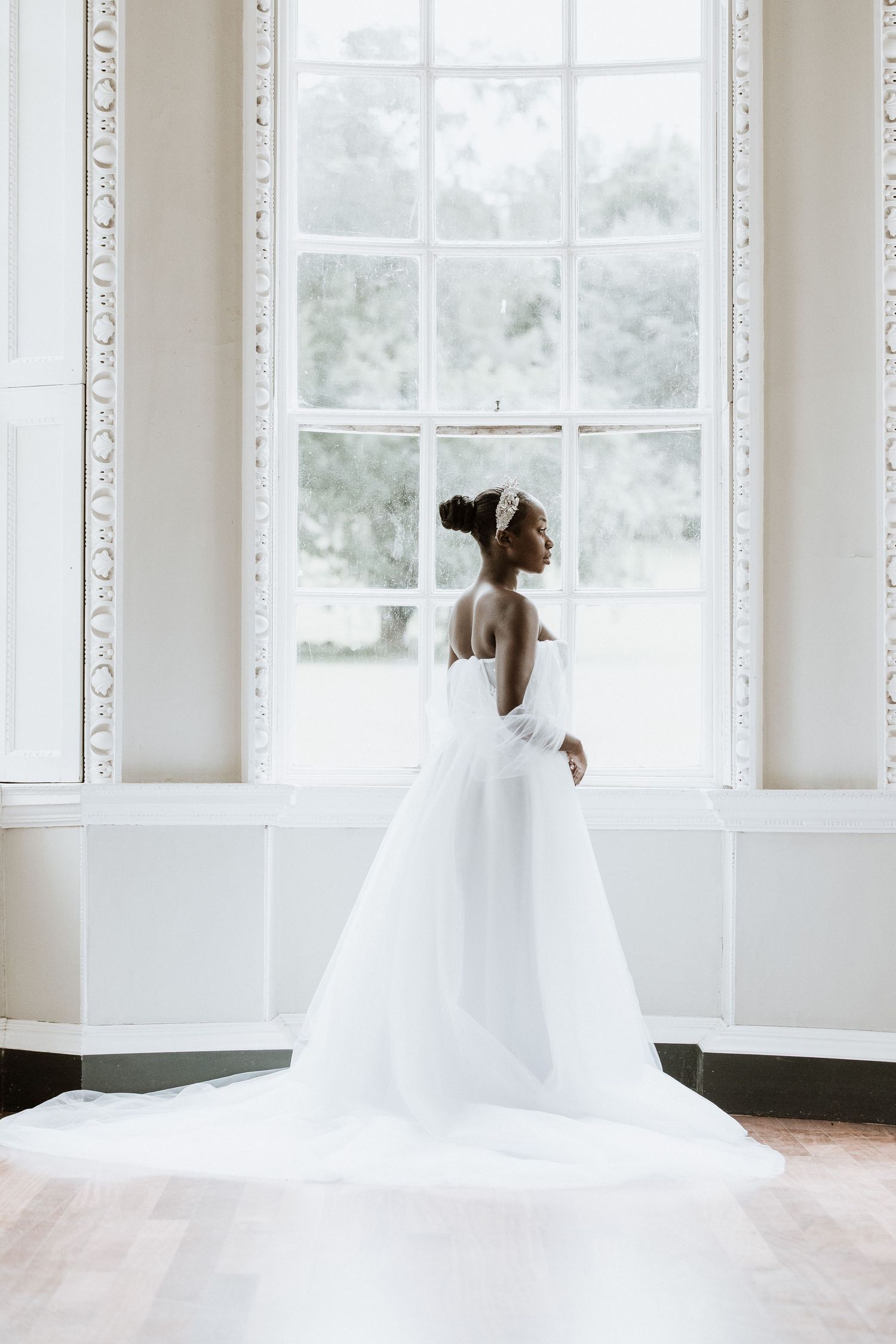 Ethereal bridal portraits in a bright white room with large windows and ornate molding.