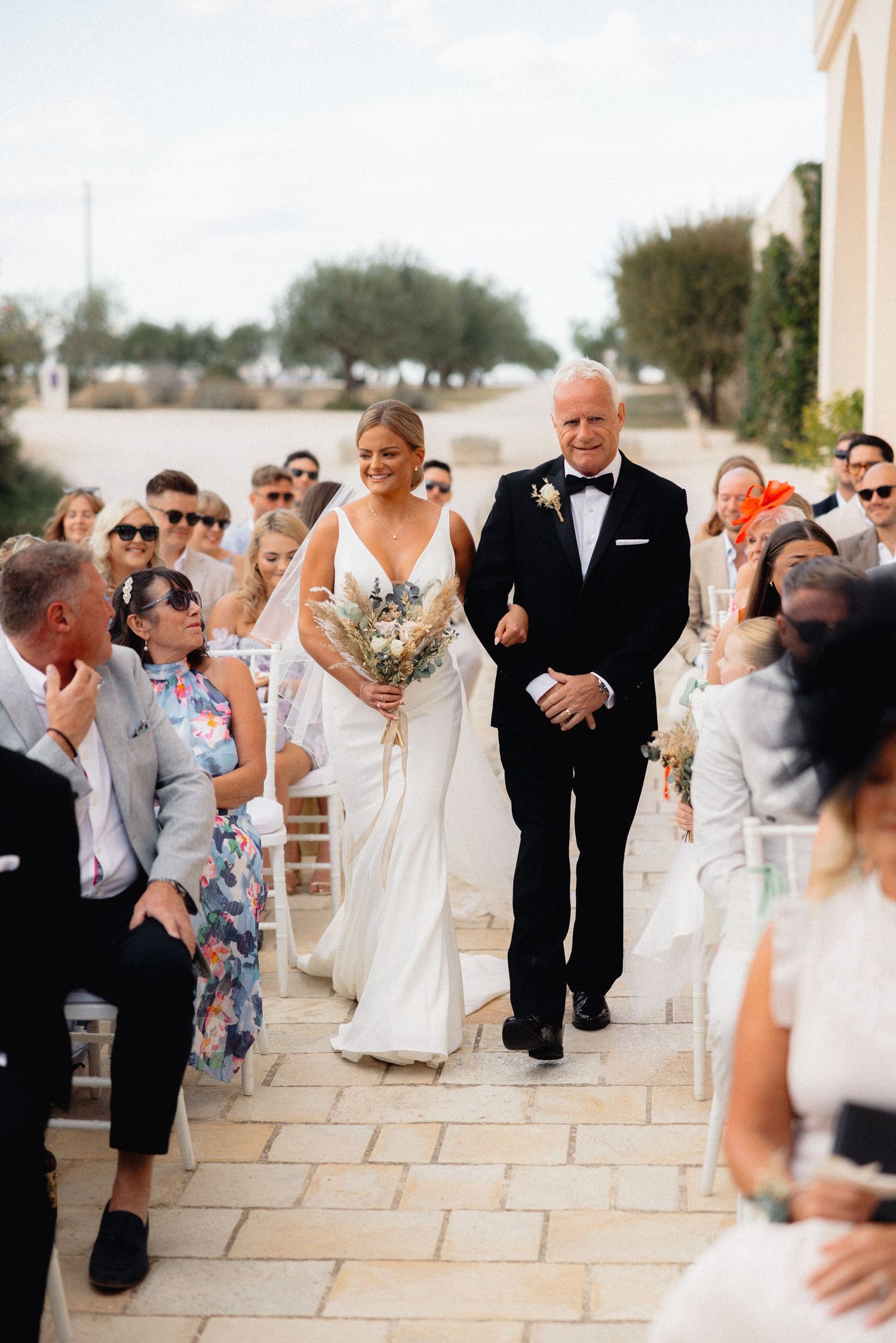 Wedding guests and wedding party members gather on an elegant stone patio during the celebration.