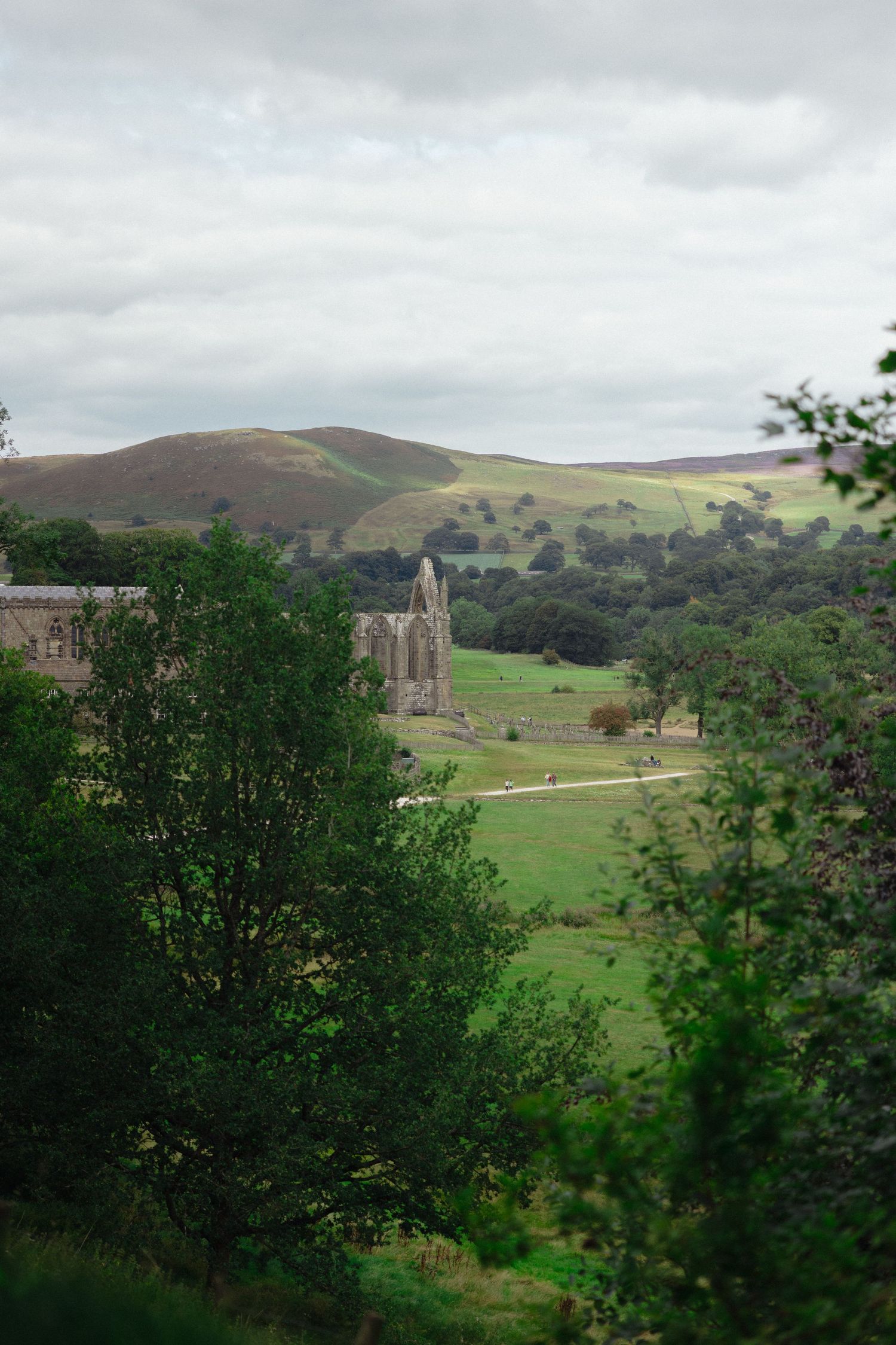 Rolling green hills and historic stone architecture create dramatic landscape vista.