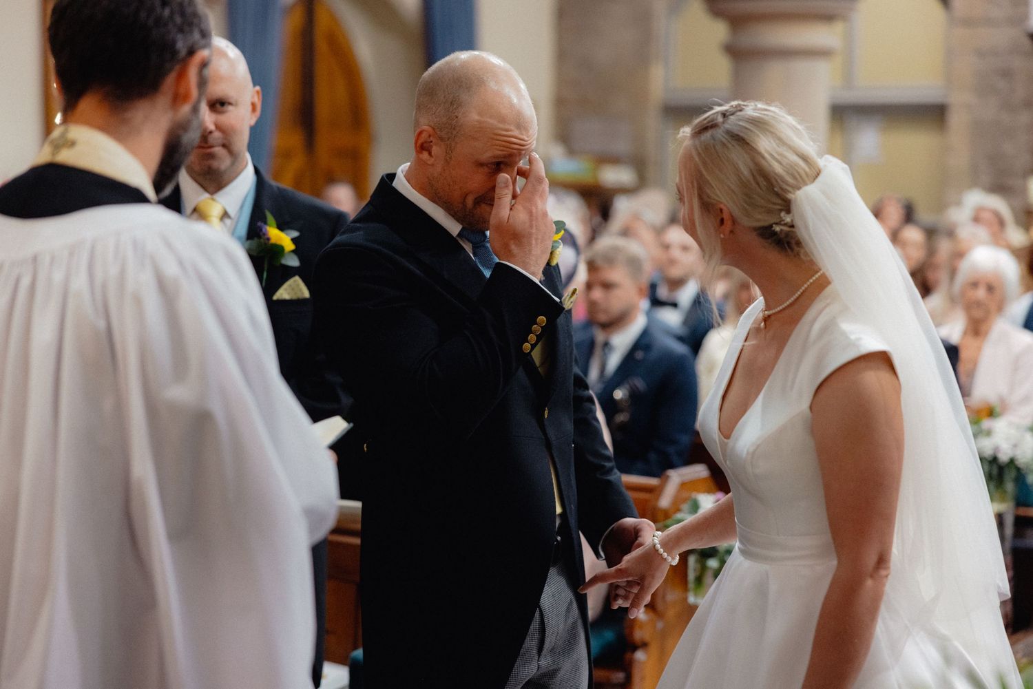 An emotional moment during a wedding ceremony in a church with a bride in a white dress.