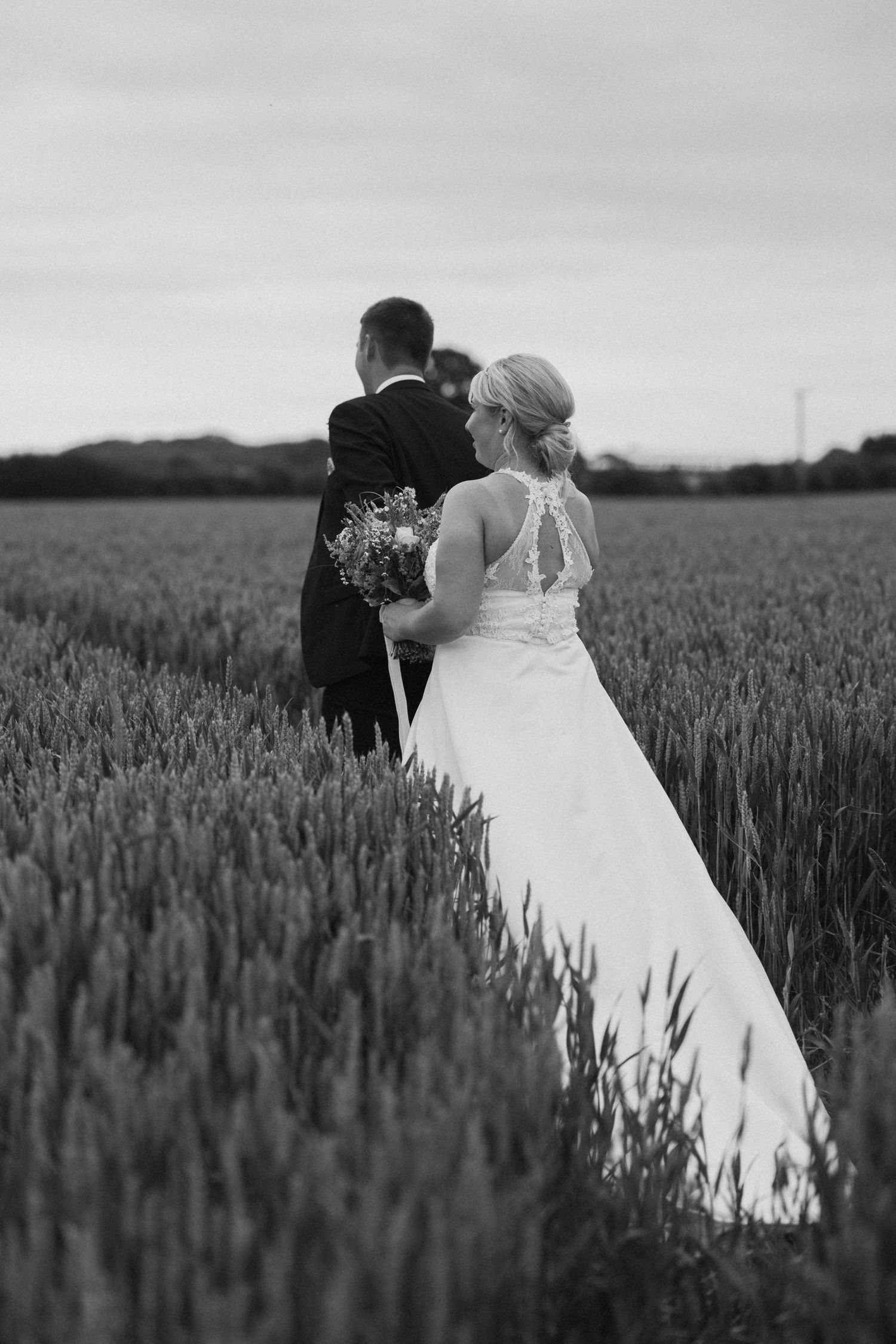 A couple poses romantically in a wheat field on their wedding day.