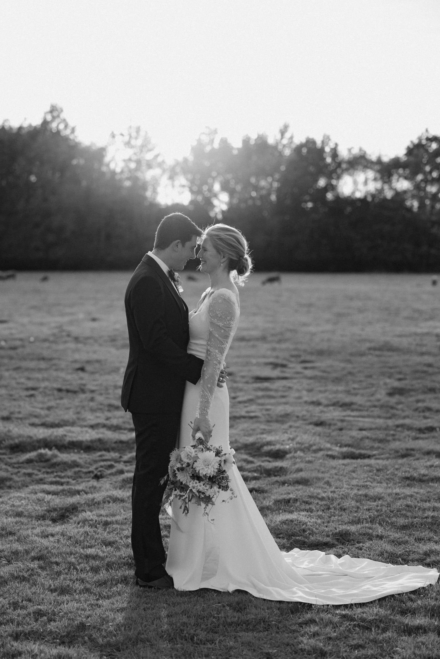 Black and white sunset portrait of wedding couple in open field.