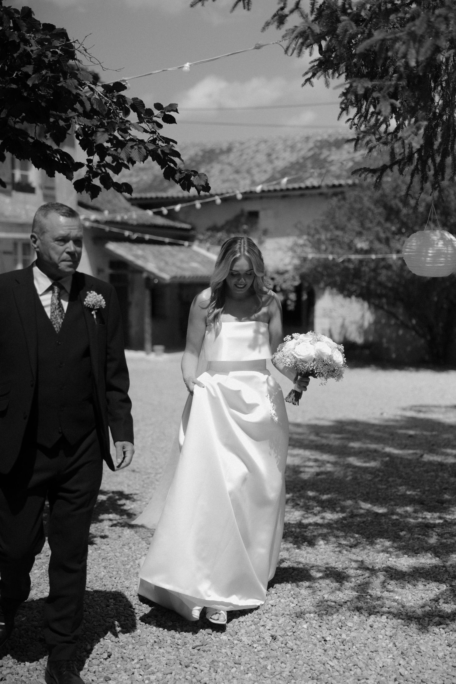 Black and white outdoor wedding scene with bride's dress flowing in the breeze.