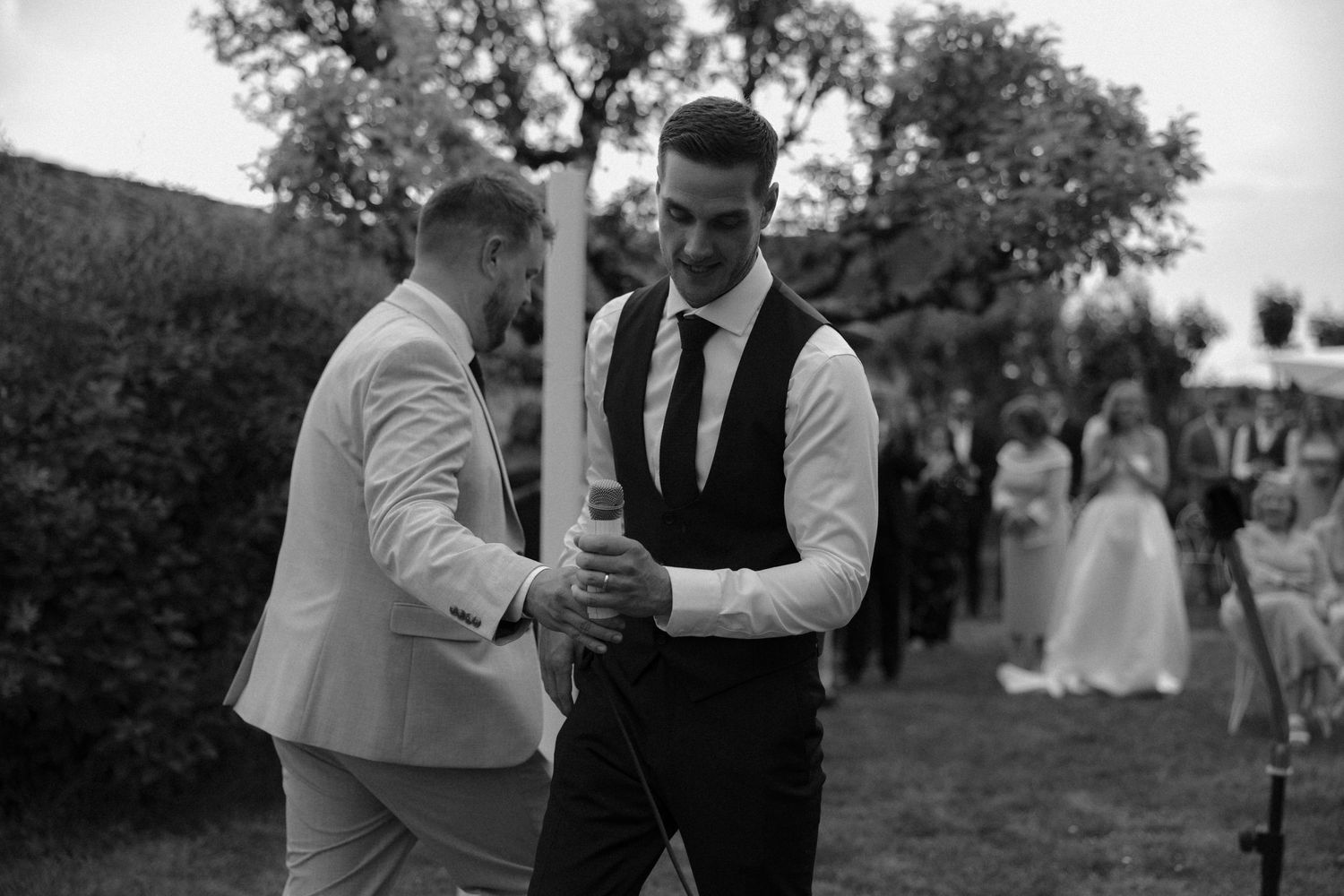 Two guests share a celebratory moment at an outdoor wedding reception.