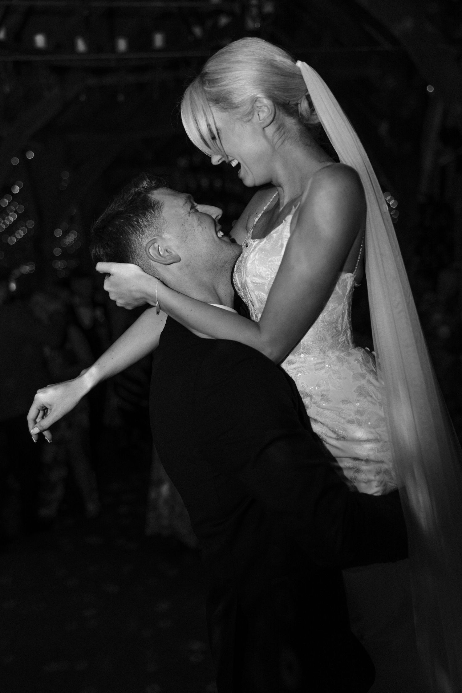 A couple shares an intimate dance moment at their wedding reception with dramatic lighting.