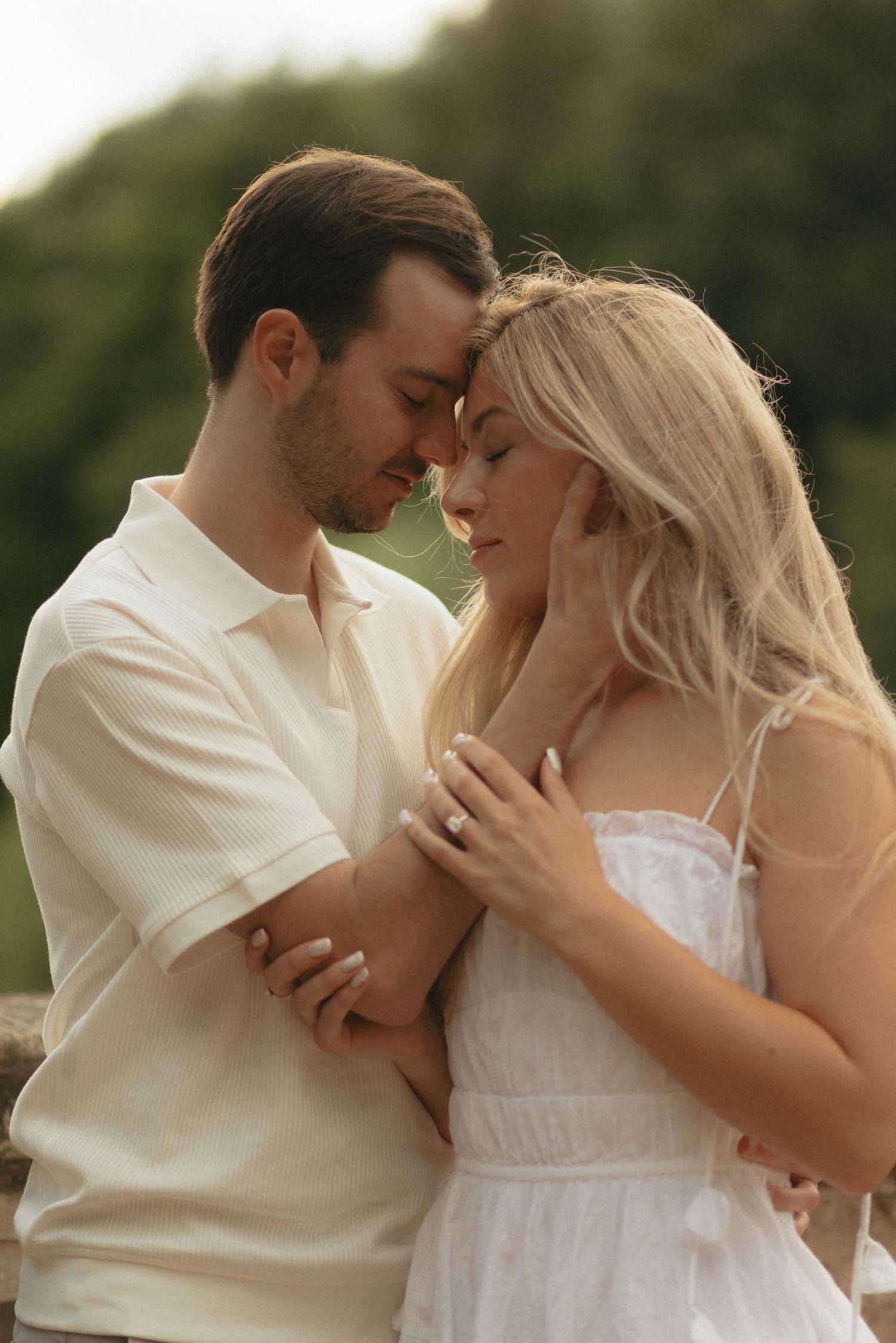 Intimate moment between couple in white clothing during golden hour photoshoot.