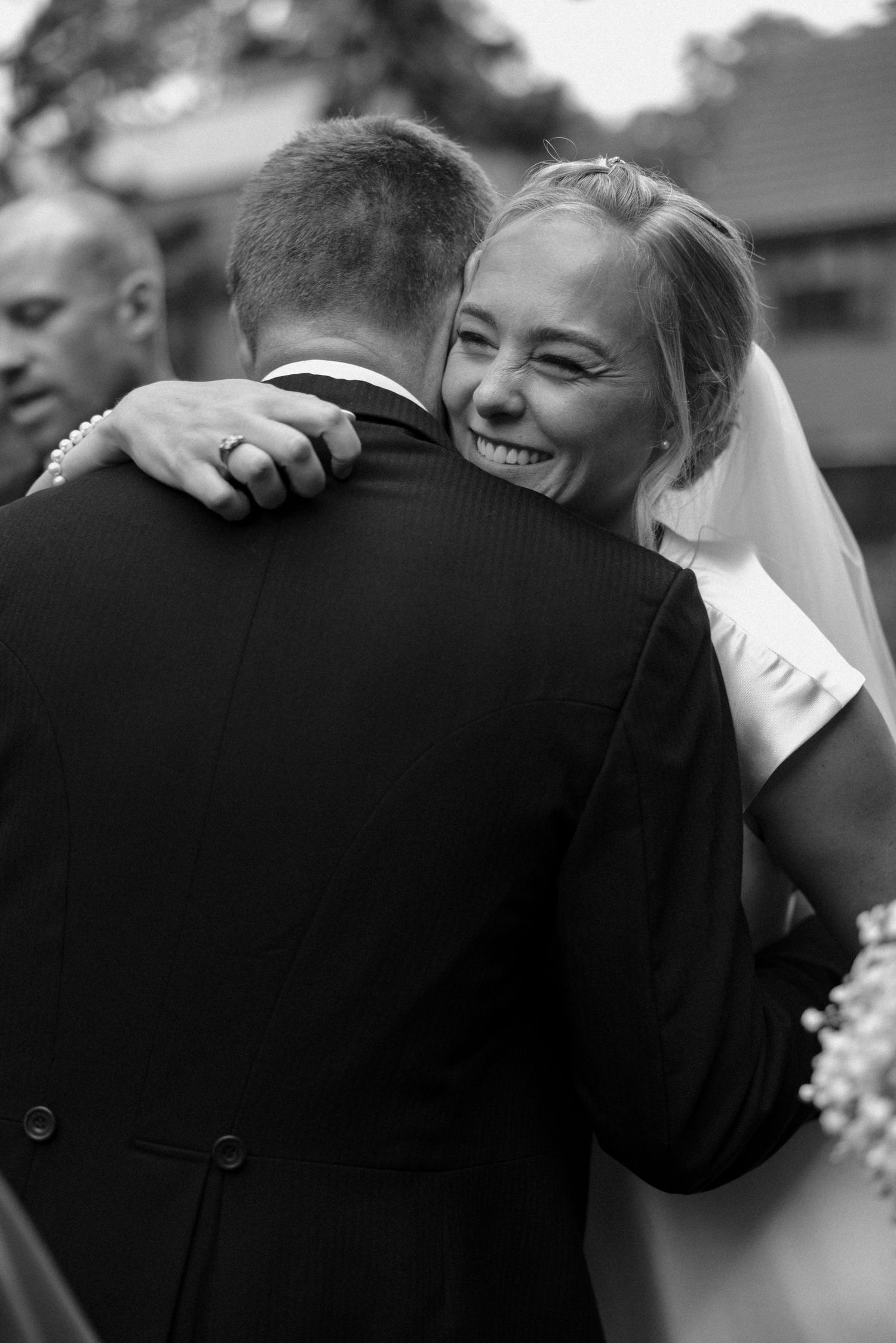 Black and white photo capturing joyful embrace during wedding celebration.