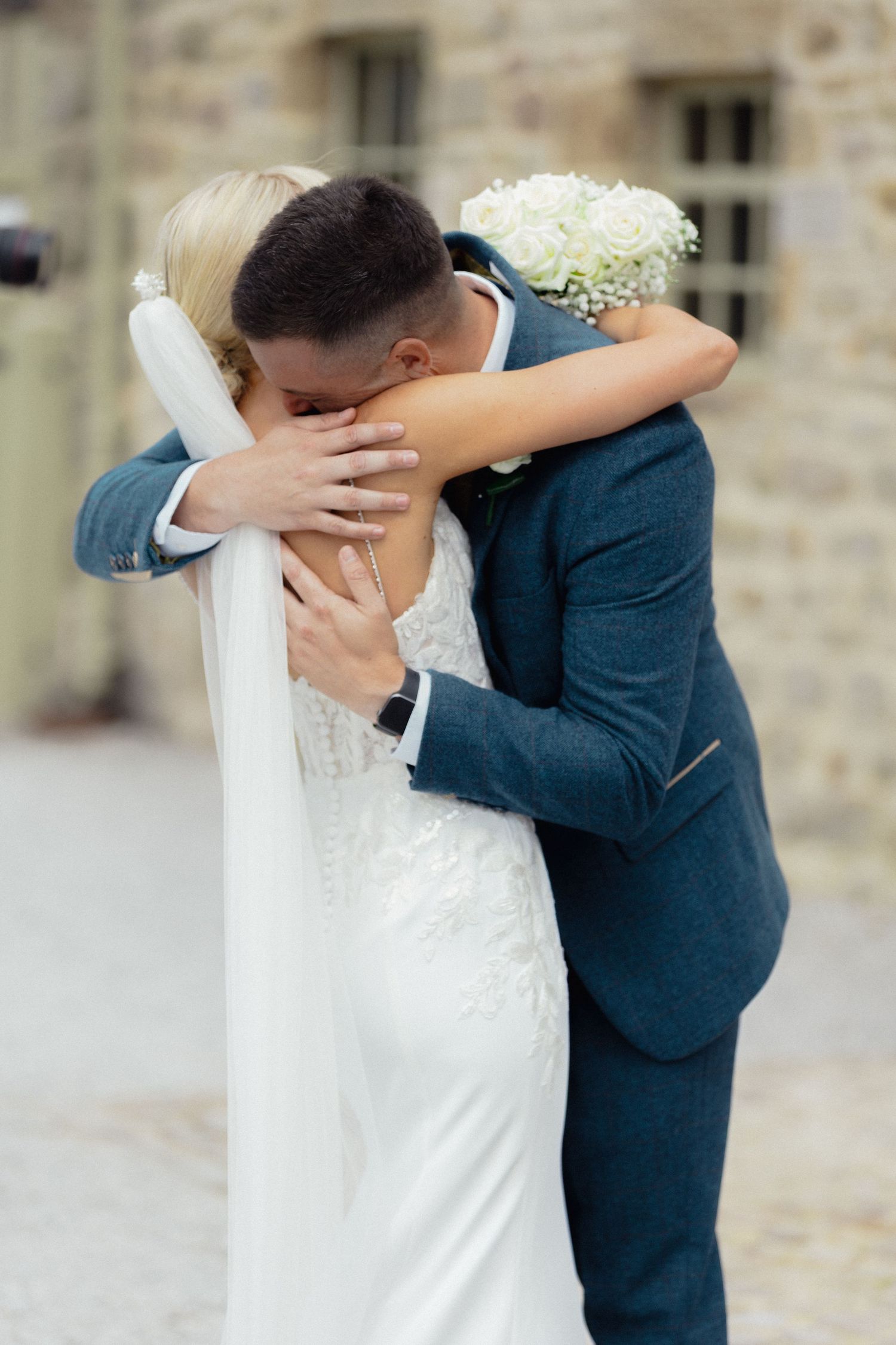 An emotional first look moment between newlyweds outside a stone building.