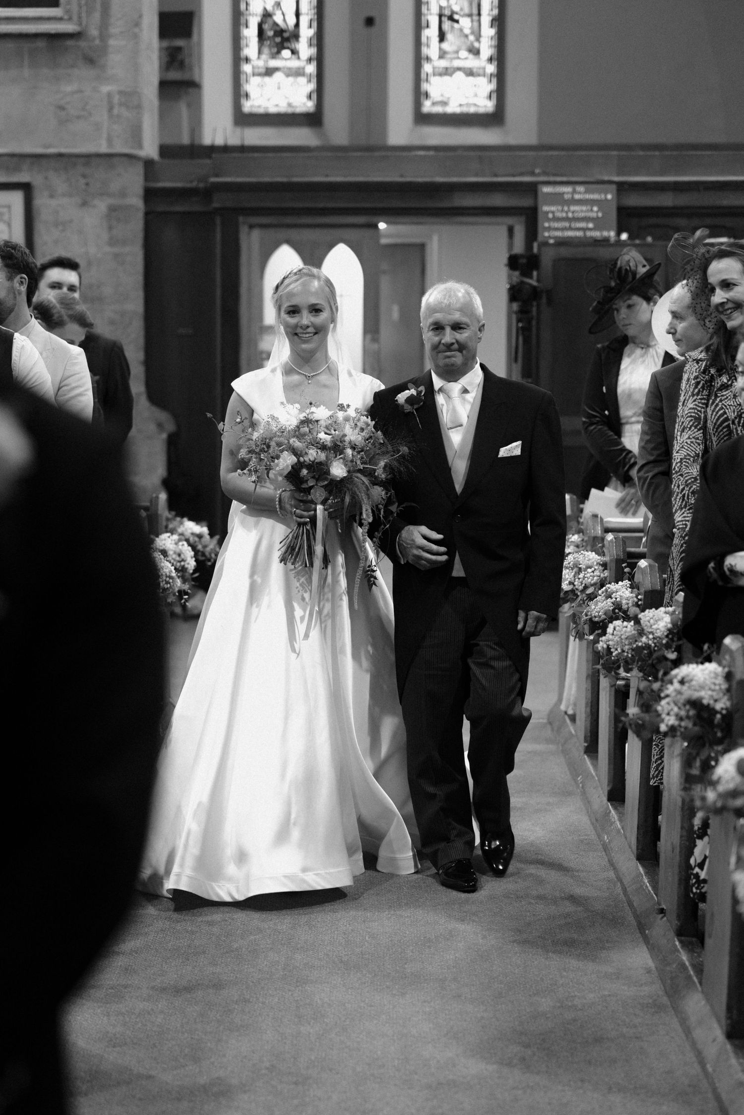 Black and white photograph of a wedding ceremony procession in a traditional church setting.