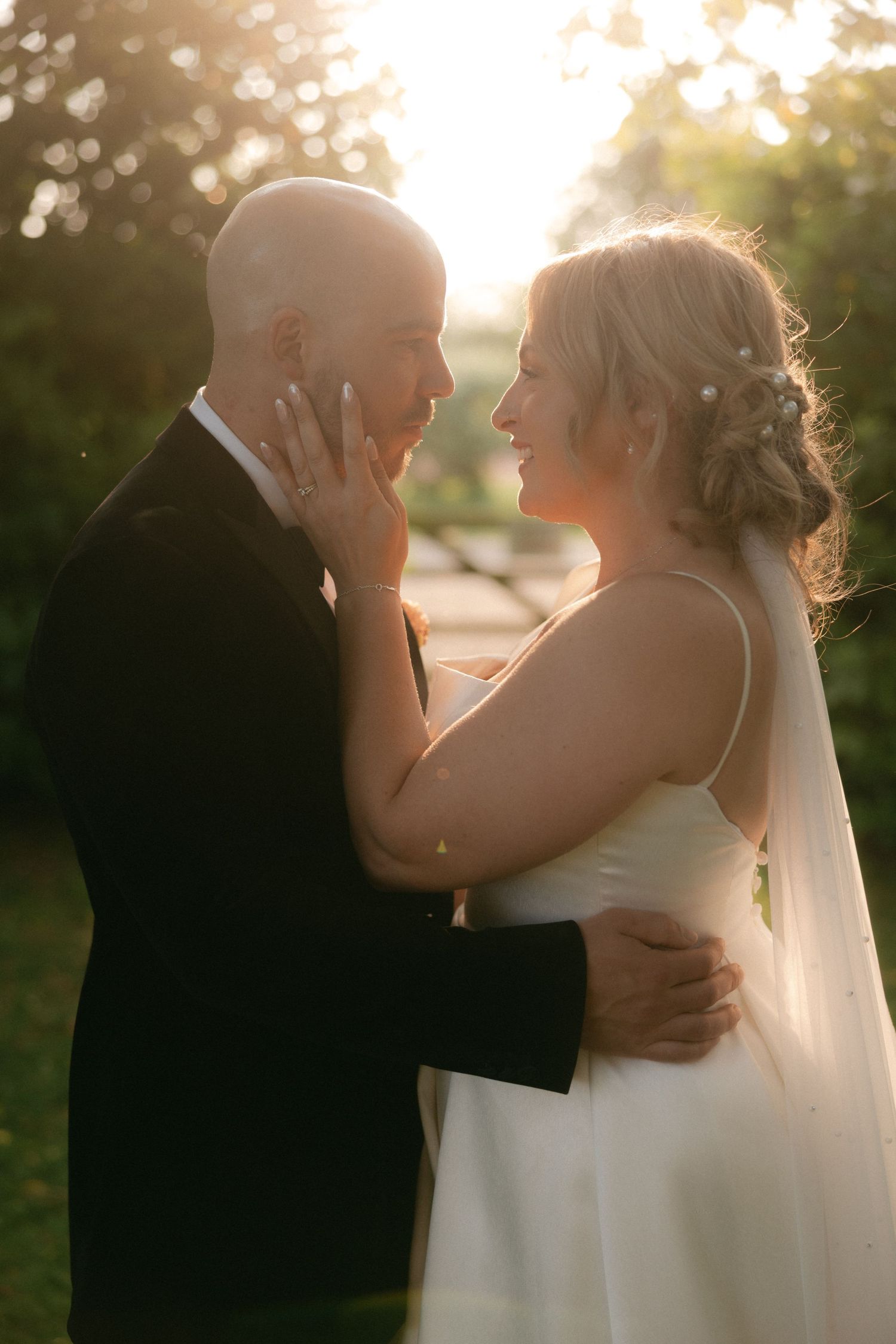 Intimate sunset portrait of newlyweds sharing tender moment in garden setting.