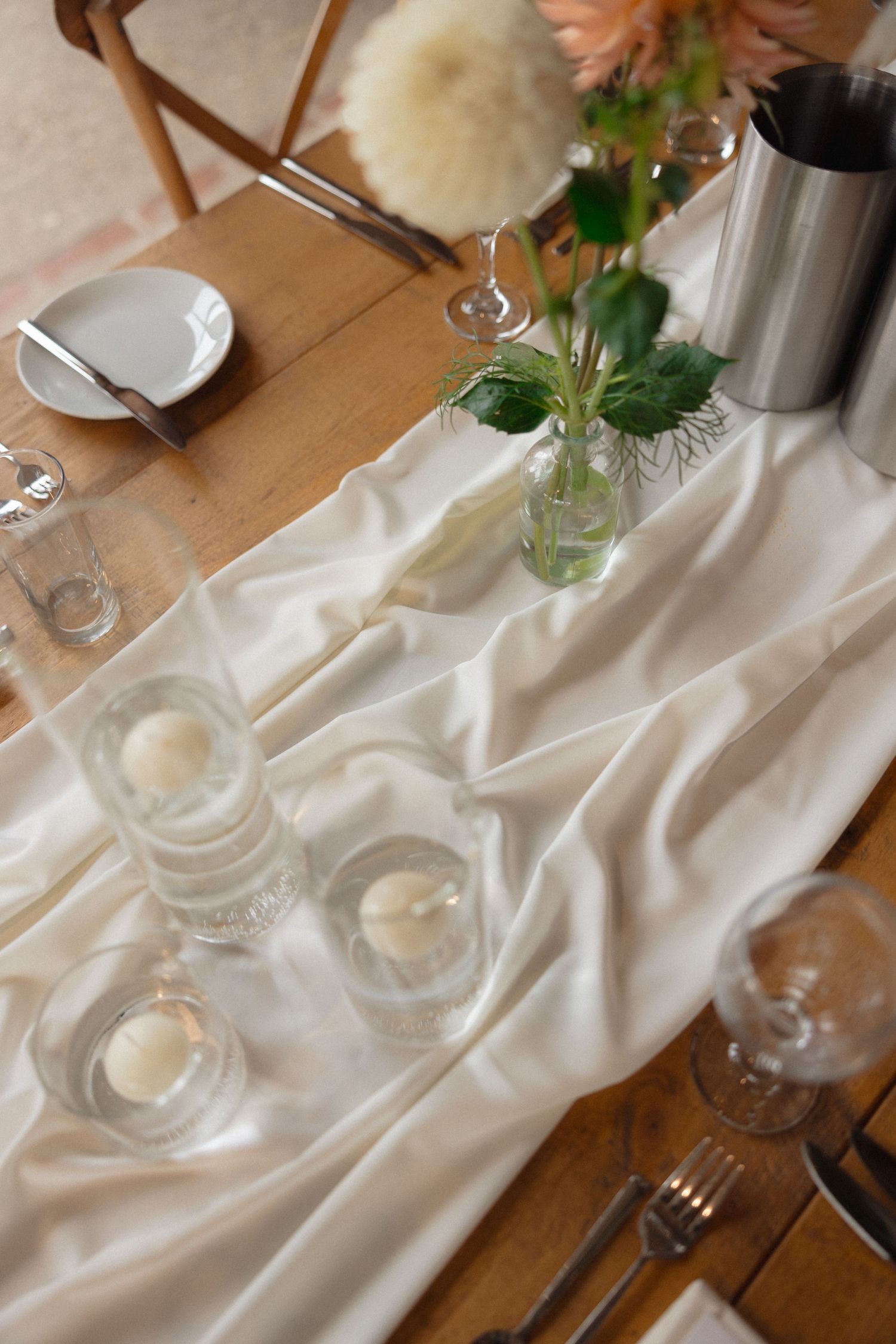 Elegant table settings with white linens, glassware and floral centerpieces.