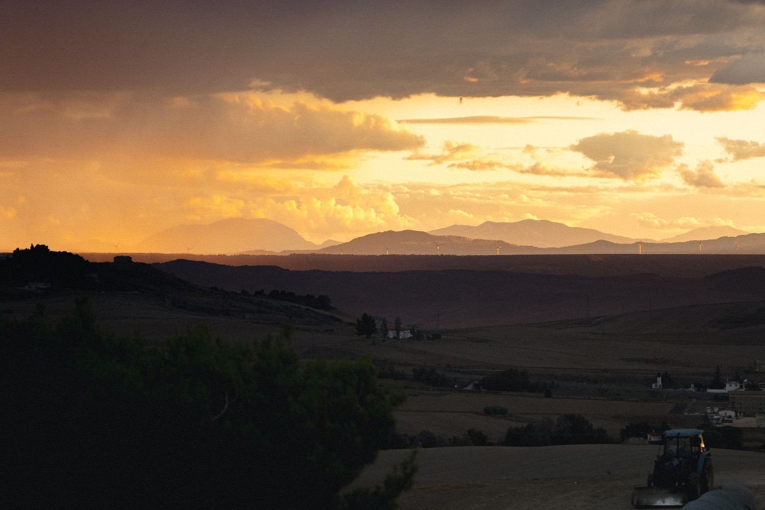 Dramatic sunset landscape over mountains with golden clouds in the sky.