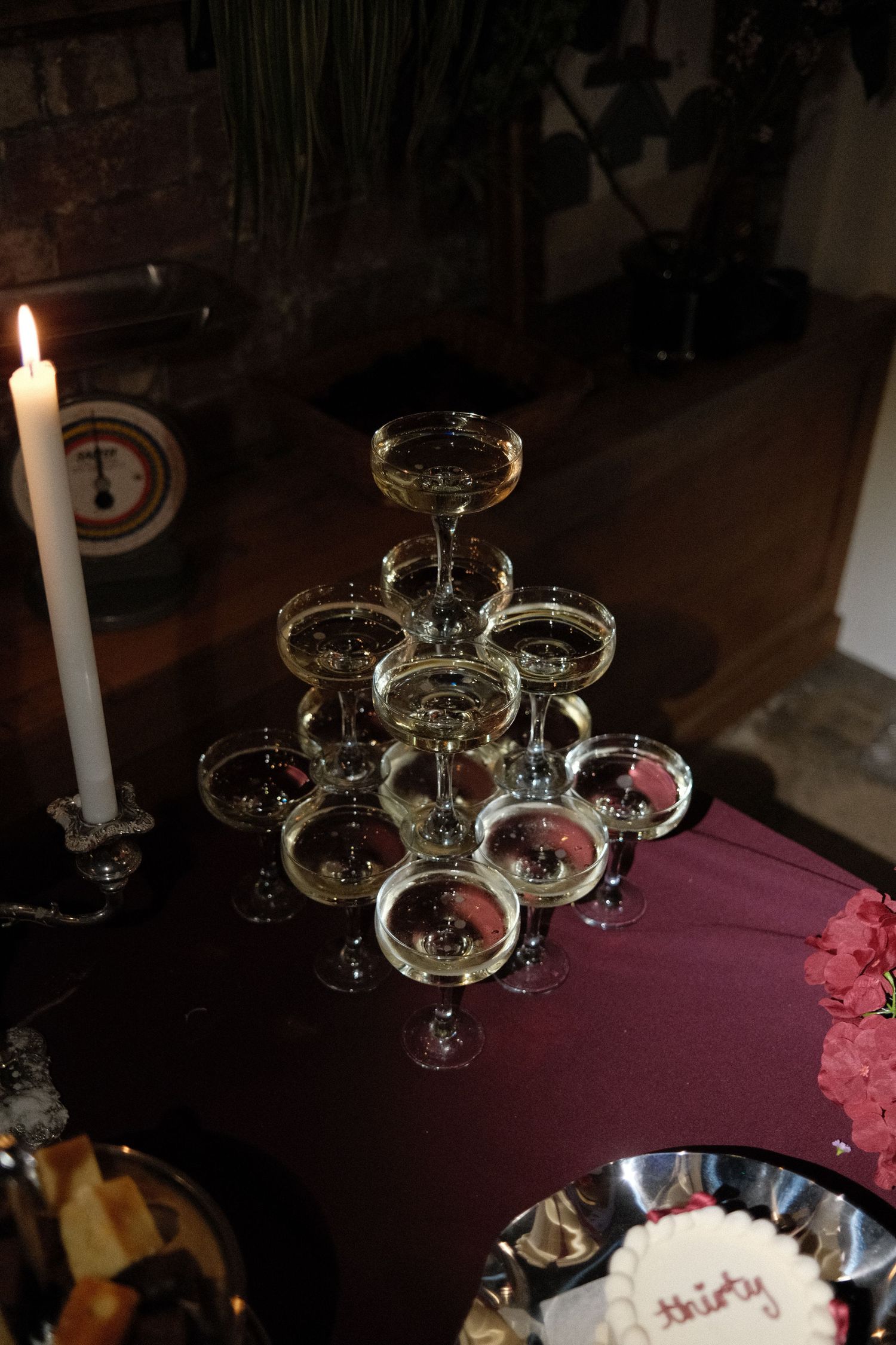 A pyramid of champagne glasses elegantly arranged with candlelight on a dark table.