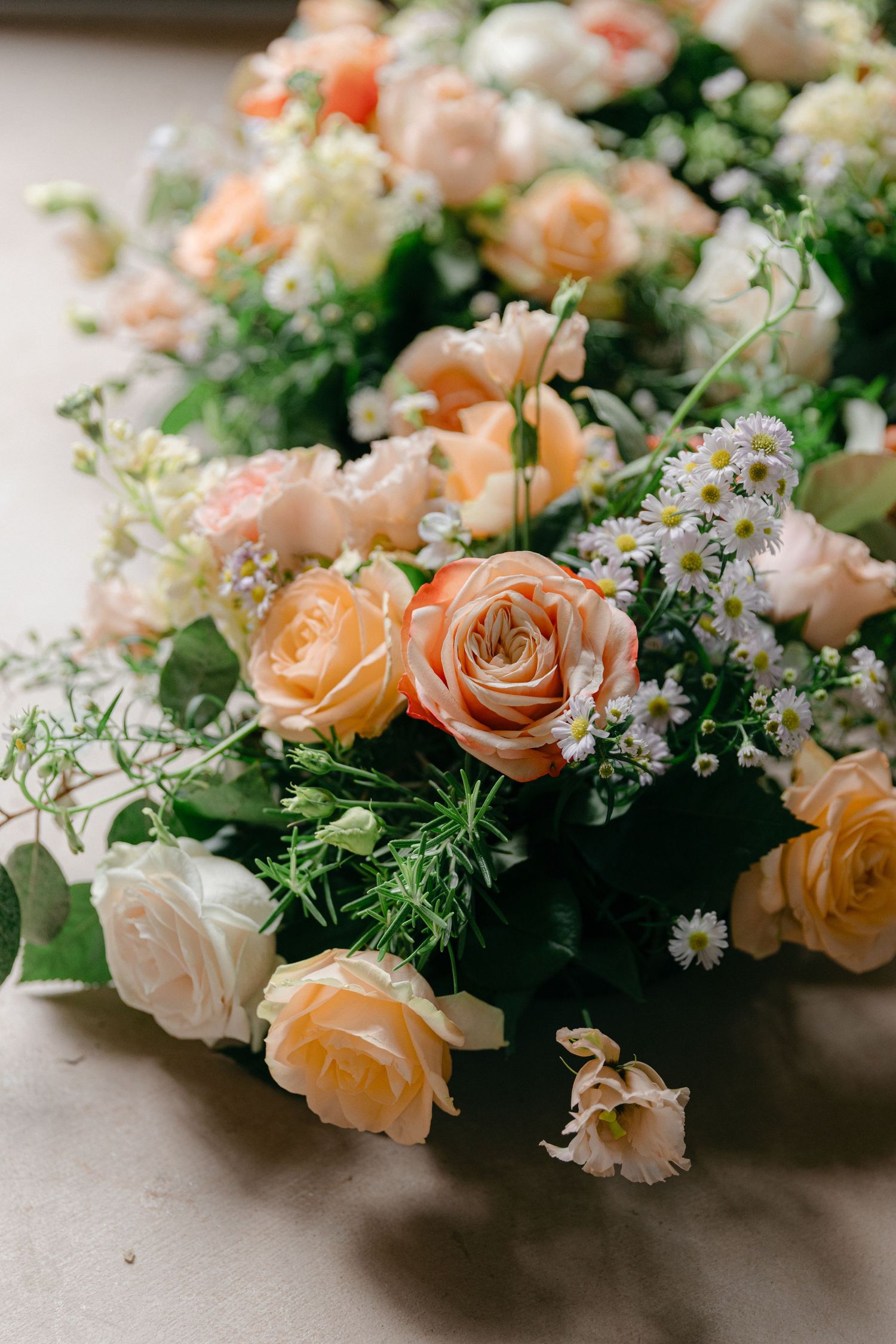 Elegant floral arrangement with peach roses and delicate white daisies.