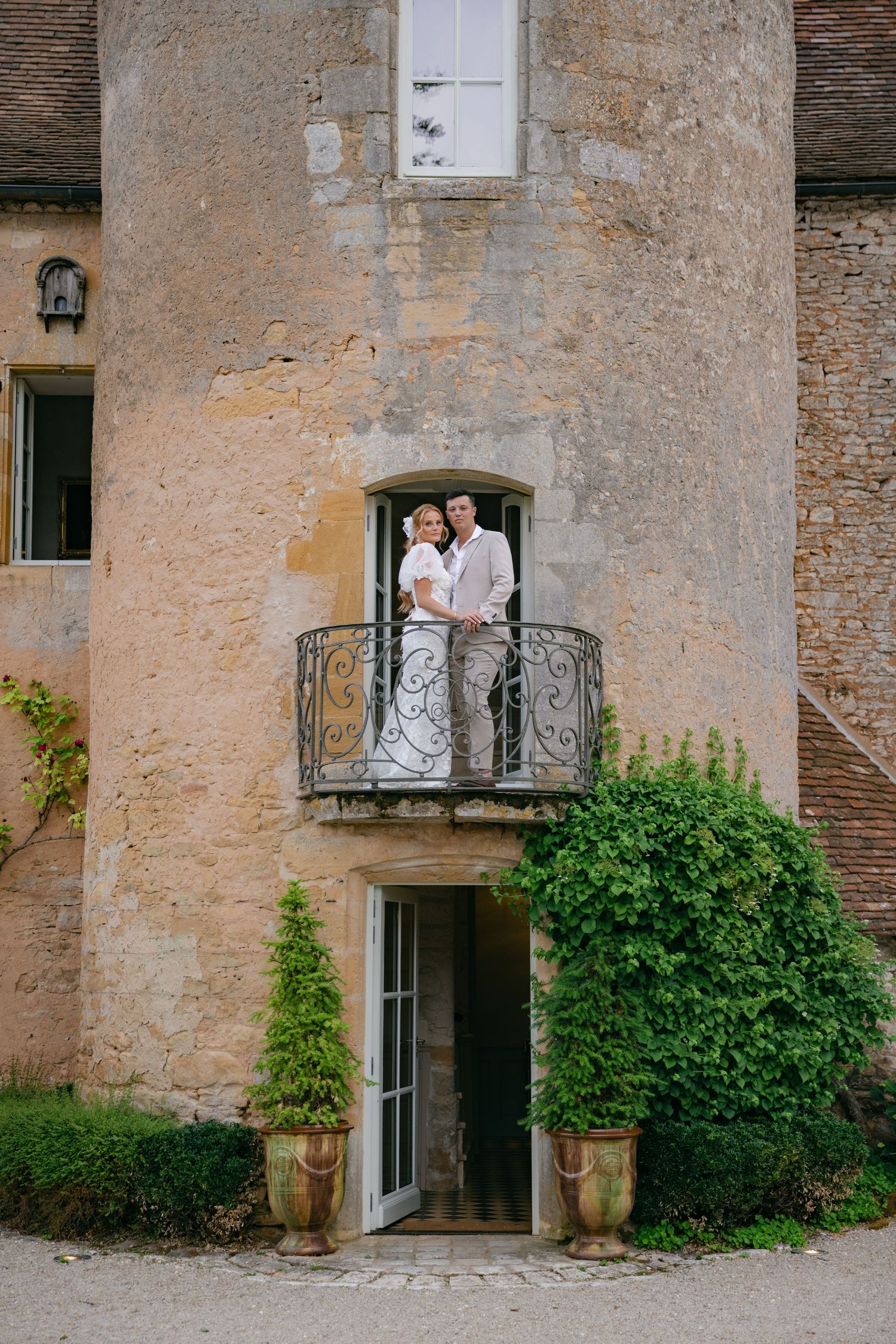 A couple stands on a rustic stone balcony of a historic building.