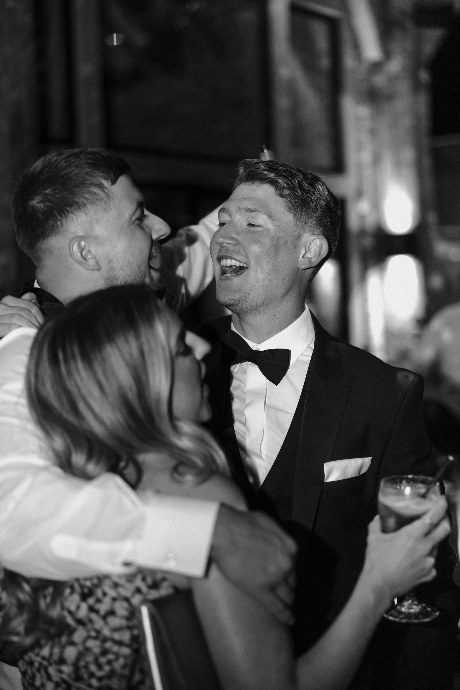 Wedding guests share laughter during evening reception.