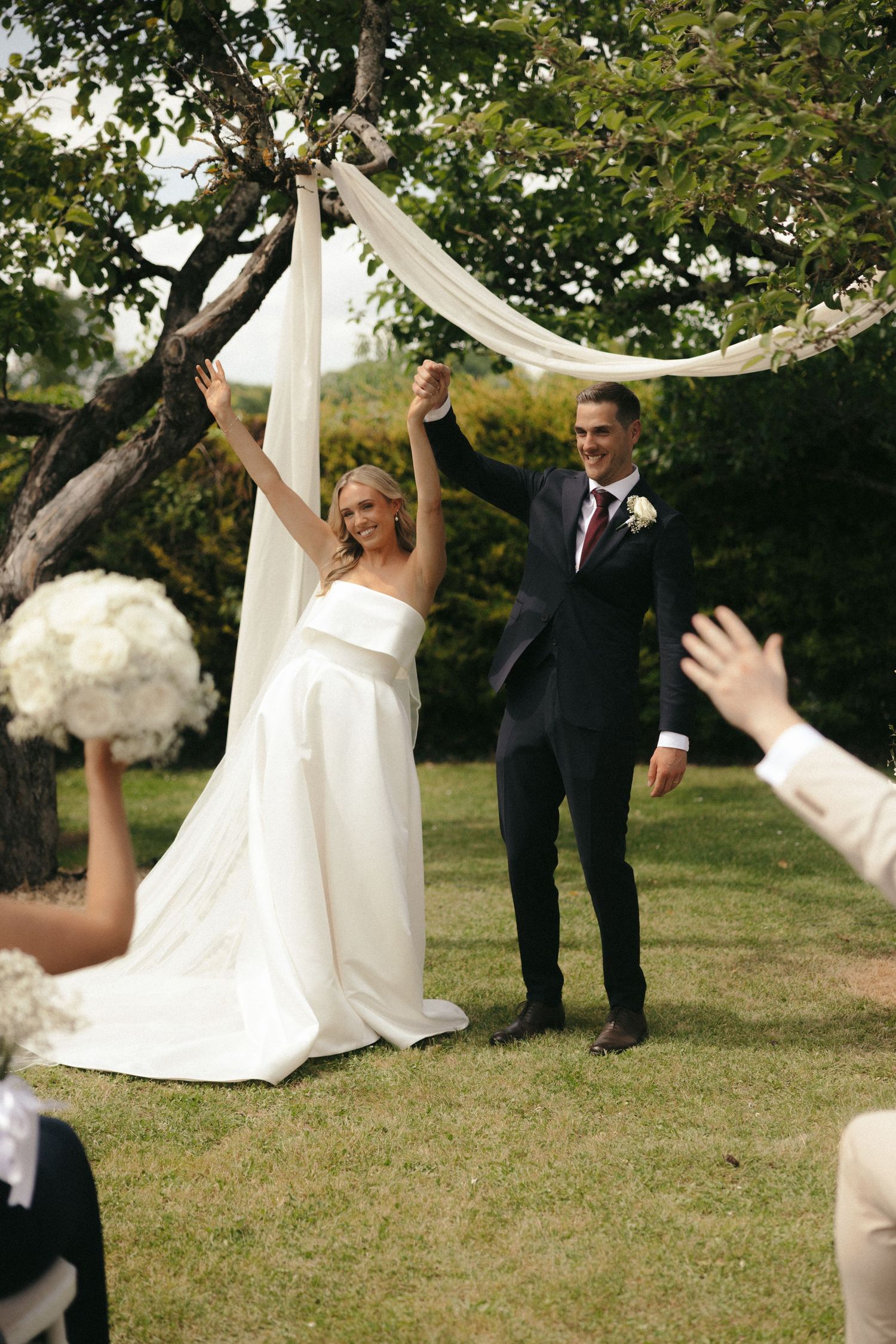 Outdoor wedding ceremony setup with white fabric draping between trees.