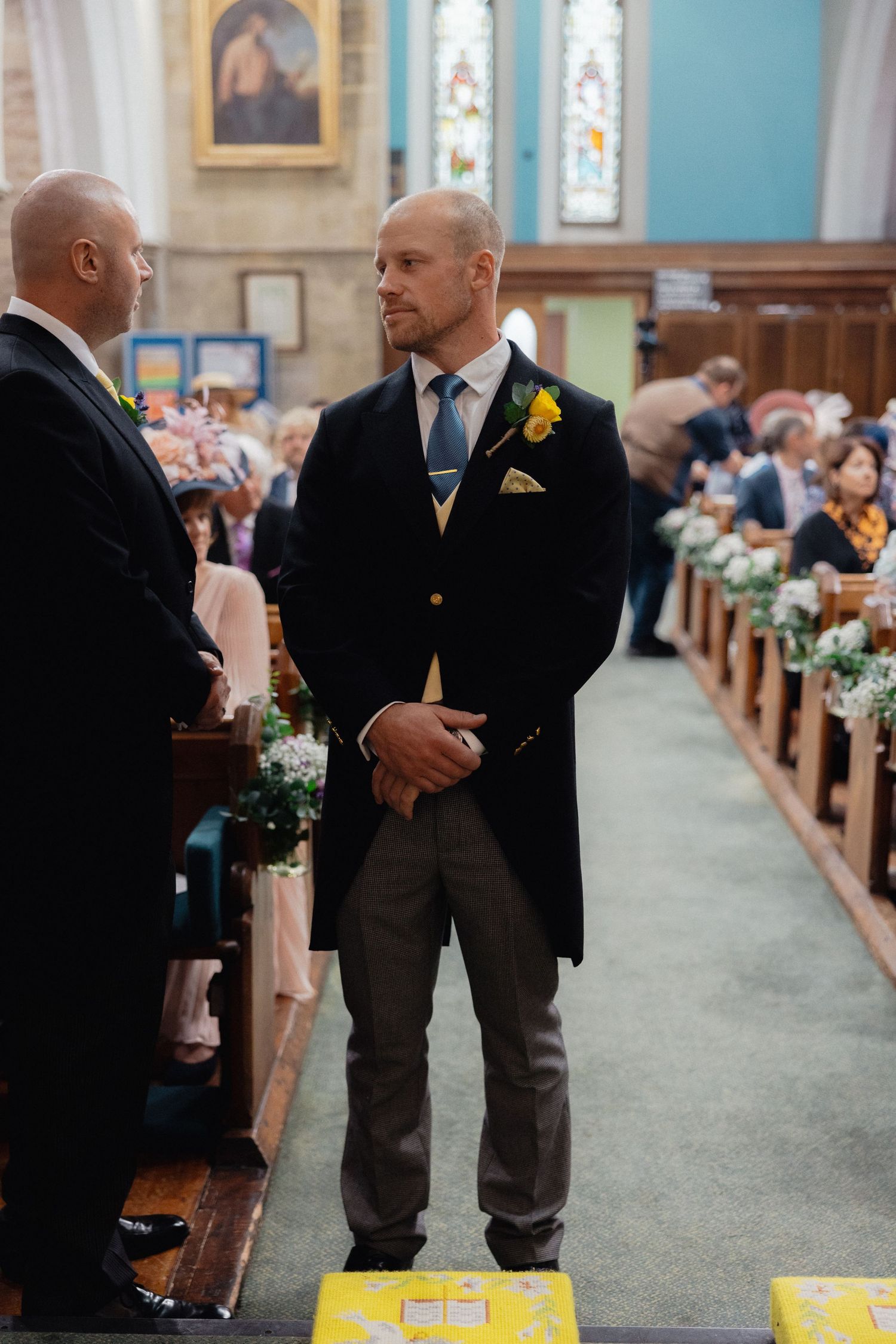 Interior of a church with turquoise walls and wooden pews decorated for a wedding ceremony.