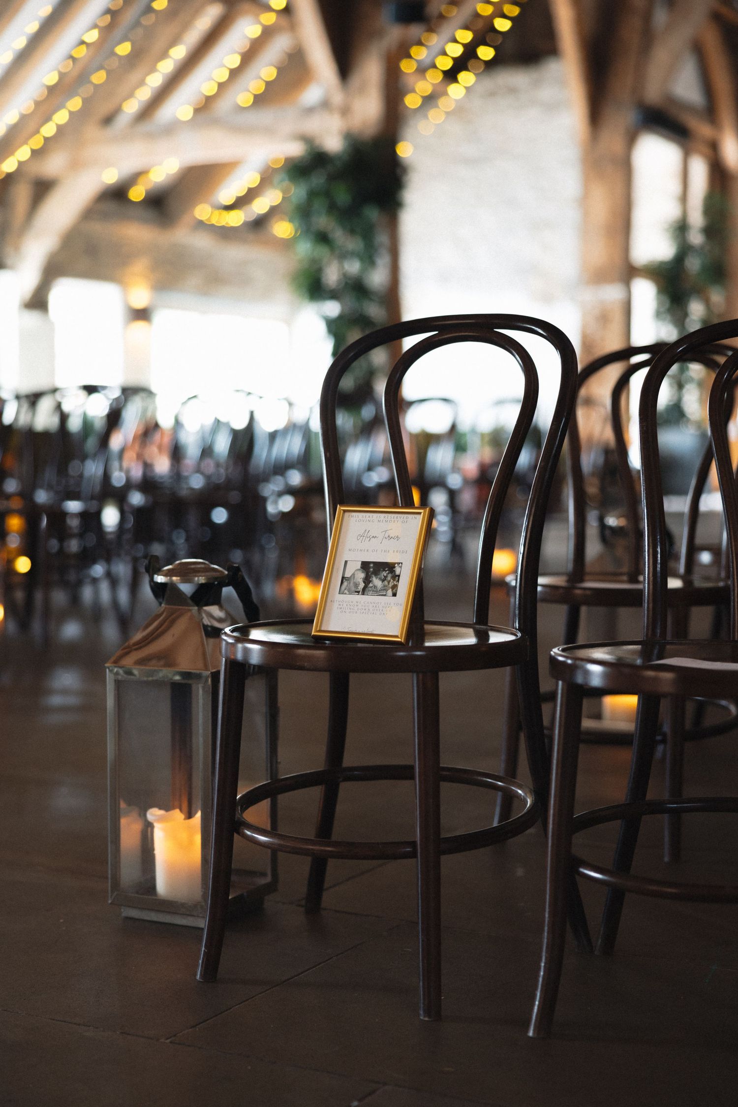 Vintage bentwood chairs with lanterns and string lights creating romantic wedding ambiance.