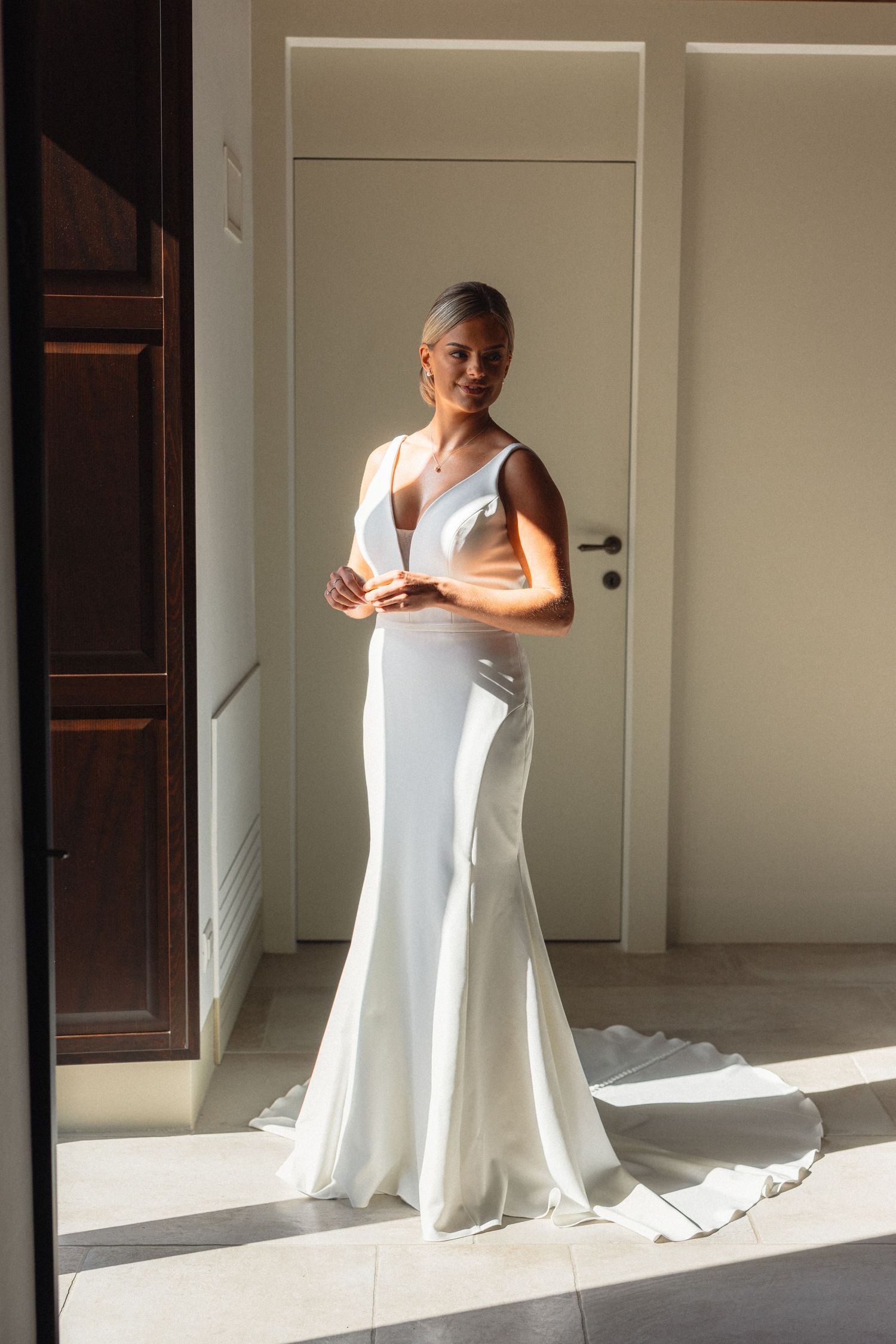 Natural light streams through window illuminating person in white formal dress.