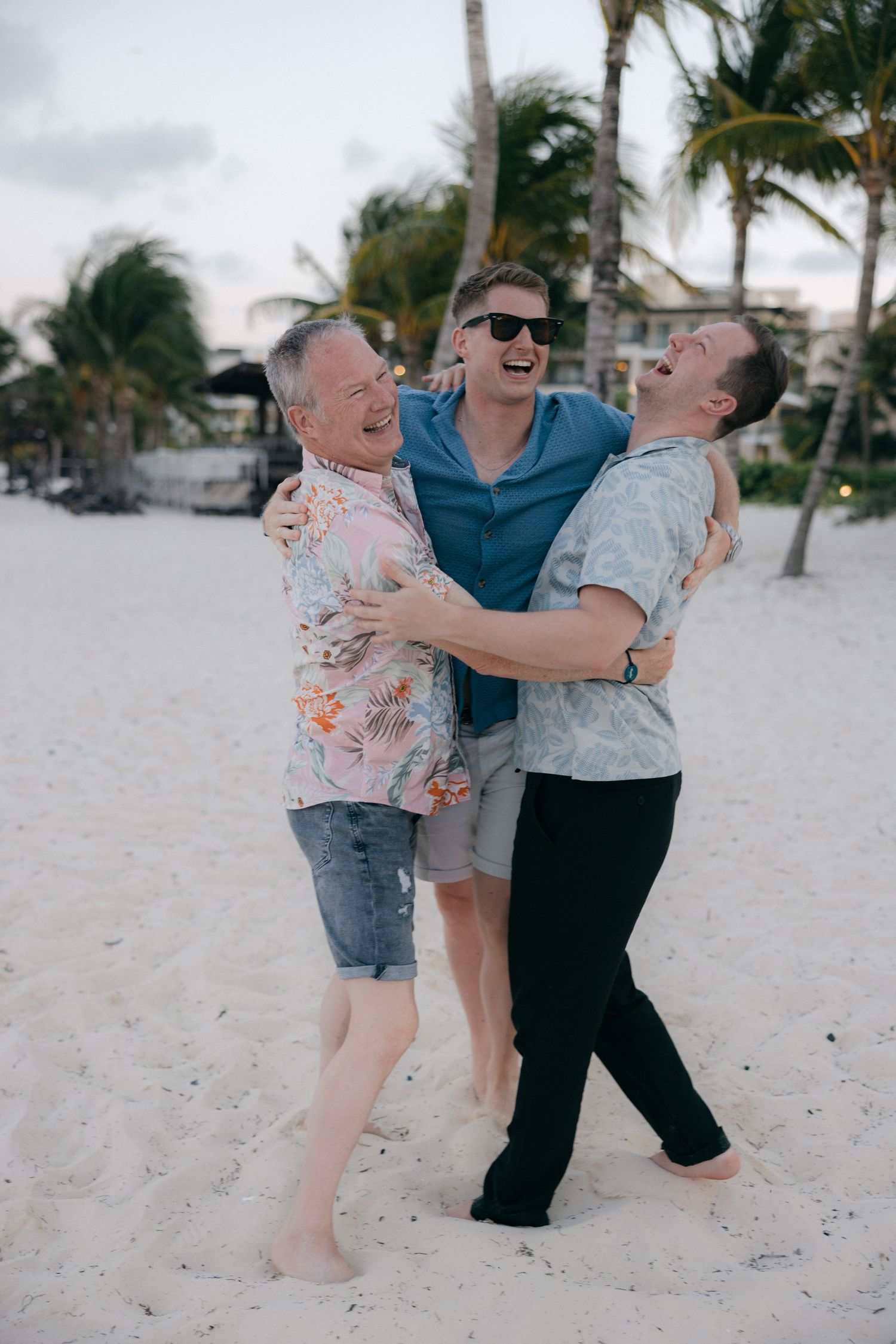 Friends sharing joyful moments and laughter while playing on a tropical beach with palm trees.