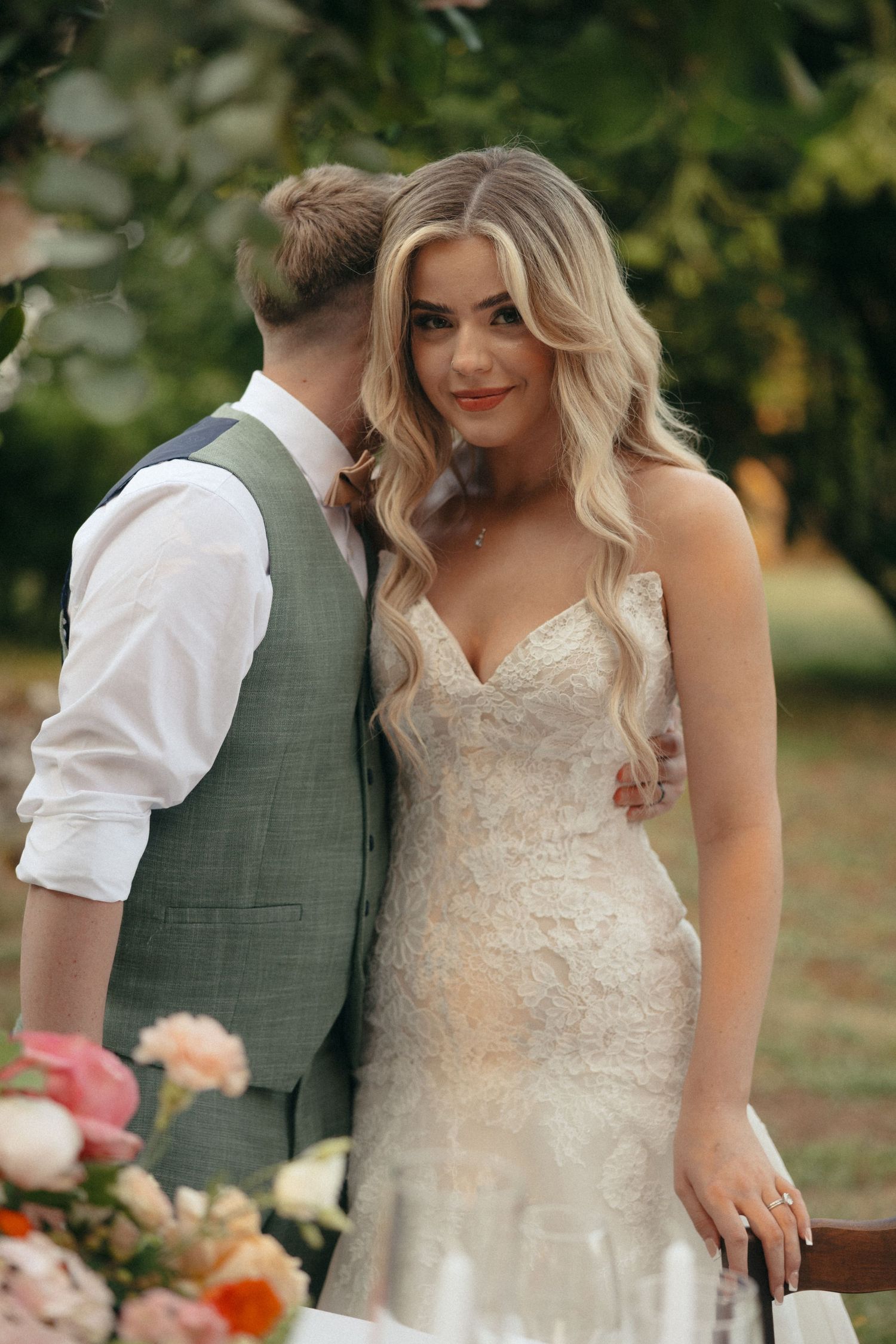 A couple sharing an intimate moment in their wedding attire outdoors.