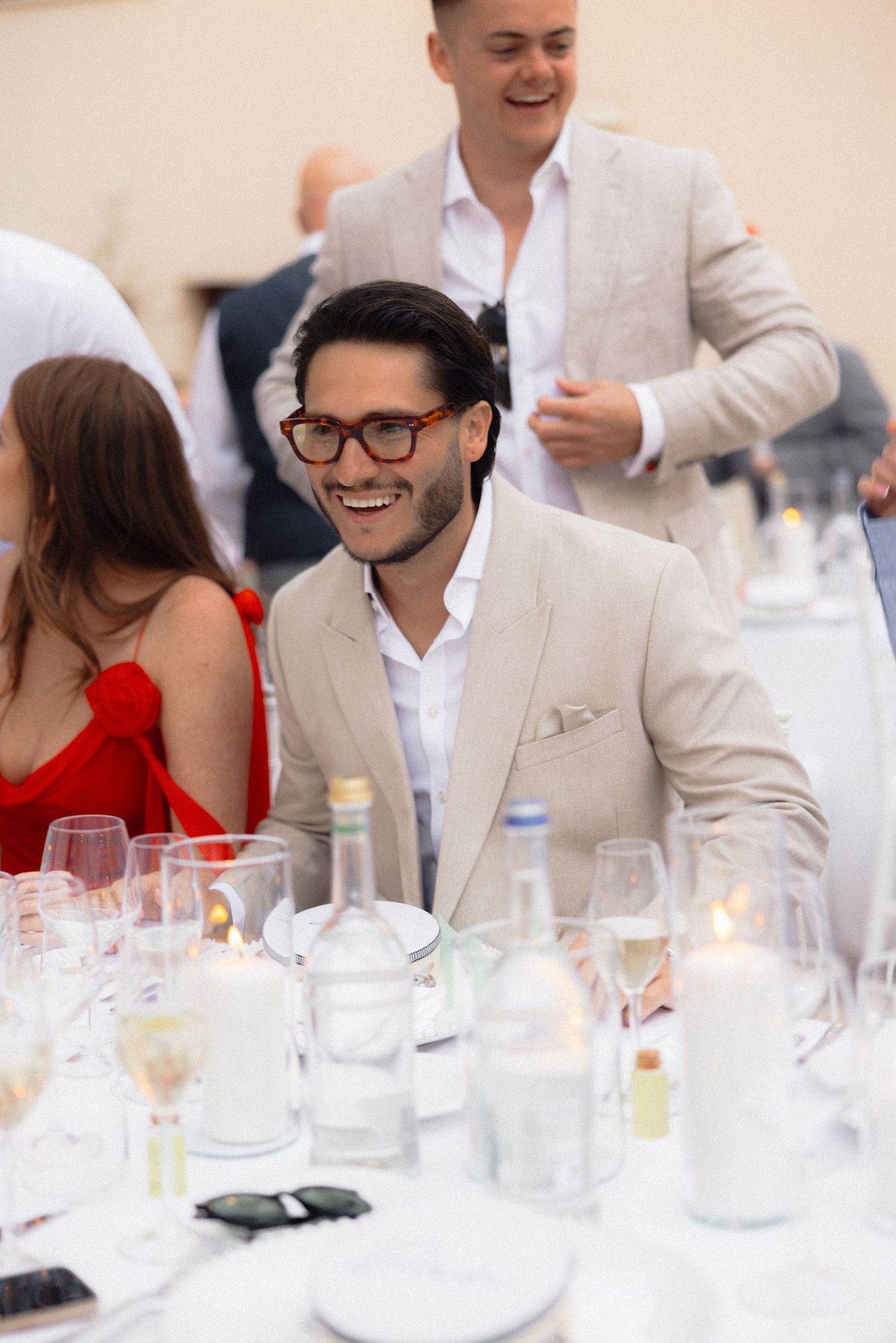 Wedding guests enjoying conversation at elegant white reception table.