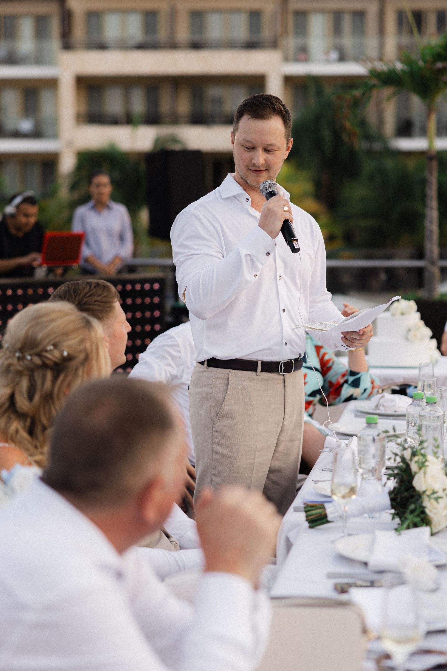 Wedding reception speech being delivered at an outdoor venue with elegant table settings.