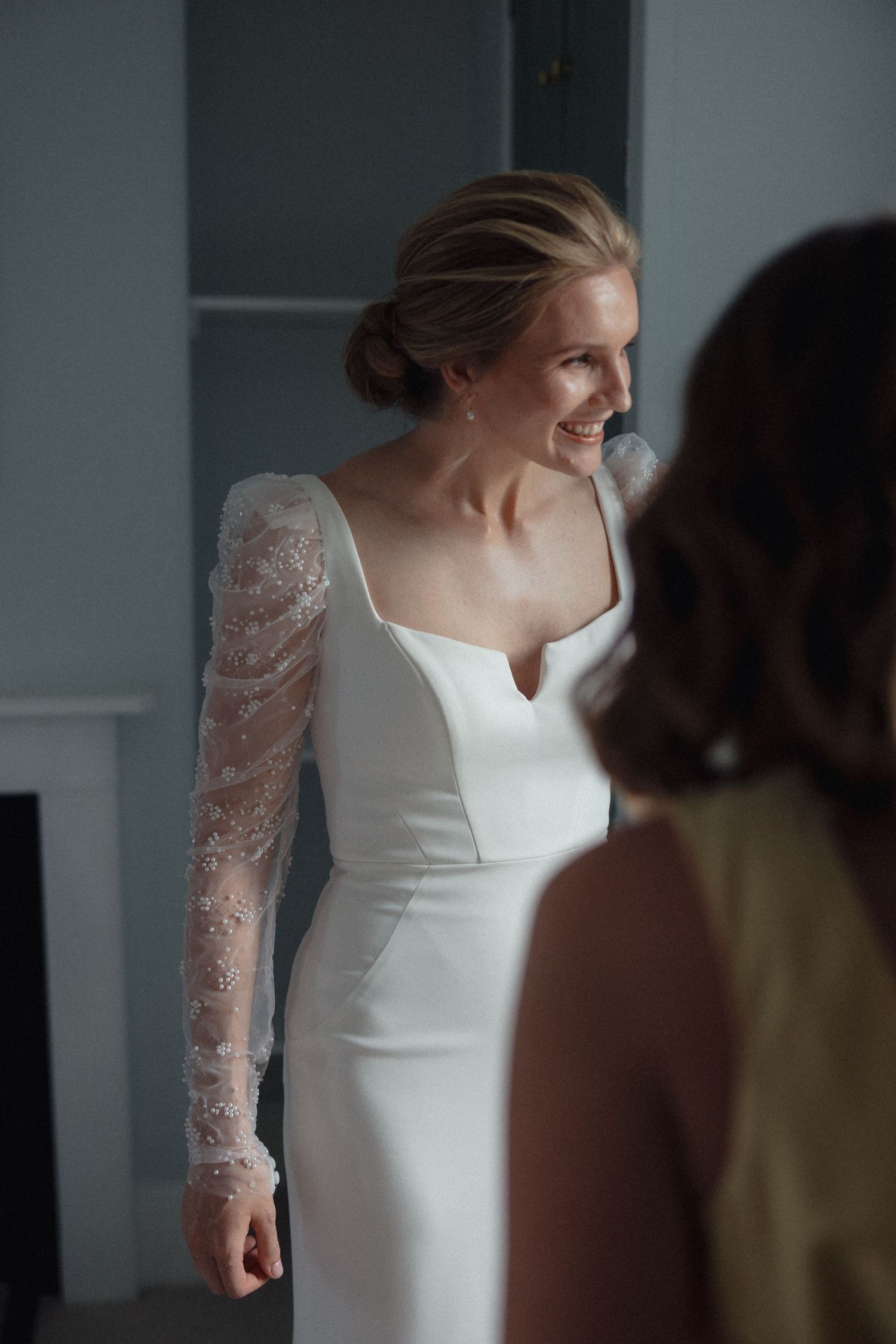 Close-up of bride in fitted white wedding gown with delicate lace sleeves.