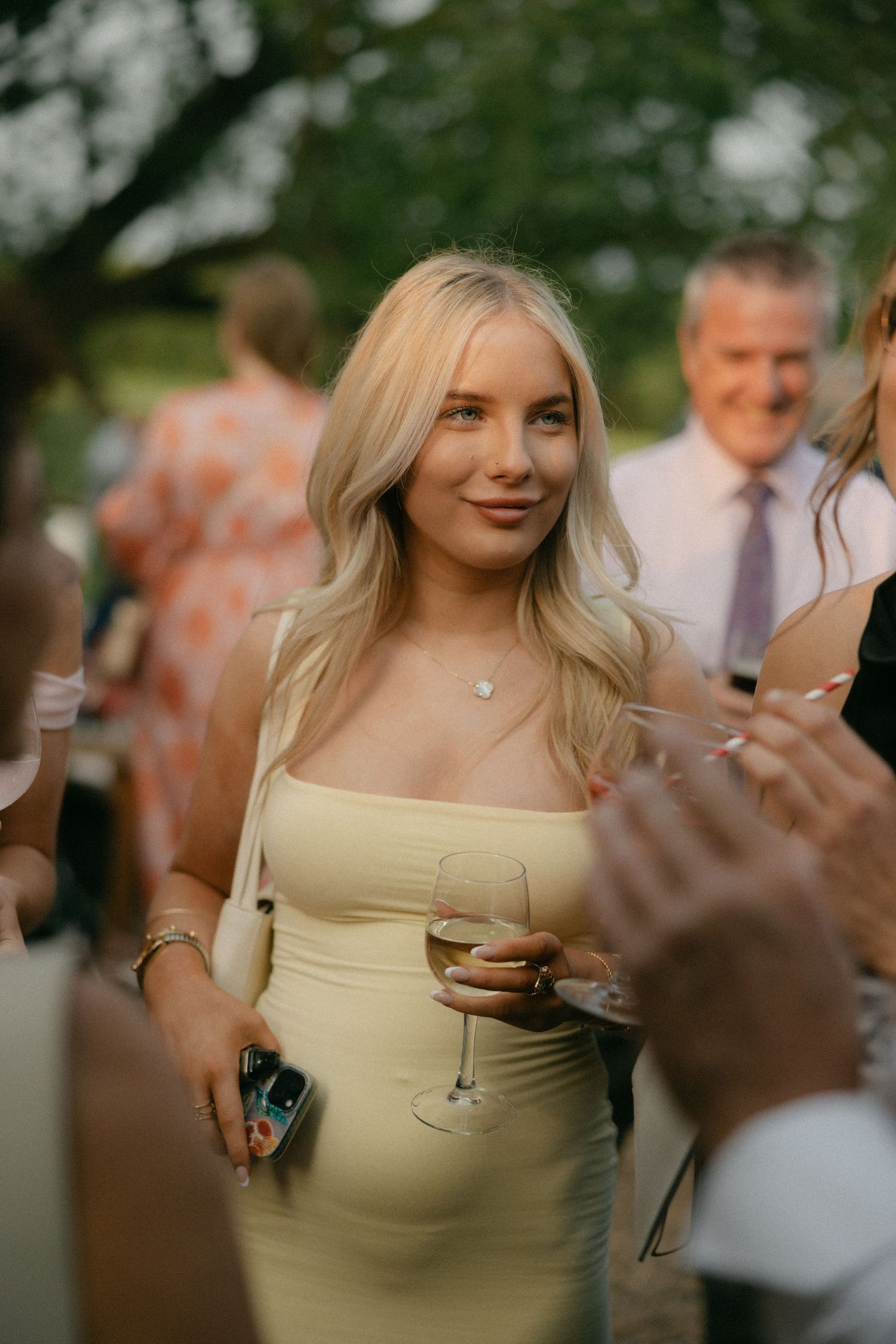 Wedding guests mingling at an outdoor reception with natural lighting.