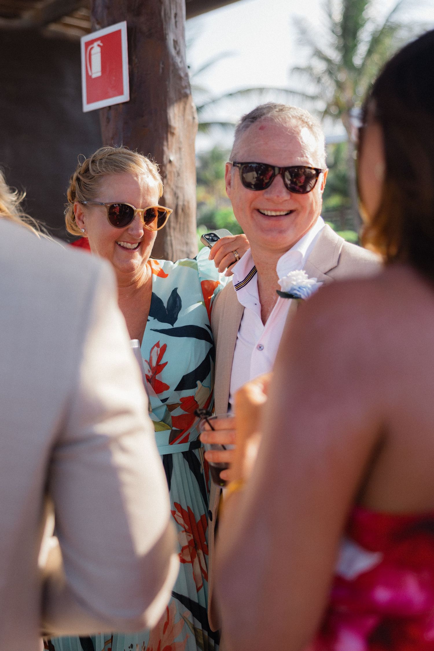 Wedding guests in colorful attire socialize during outdoor tropical reception.